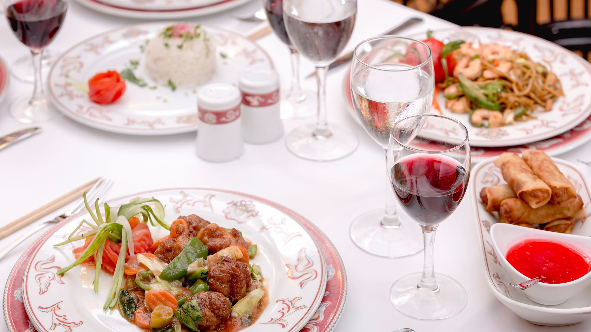 a table with plates of food and wine glasses
