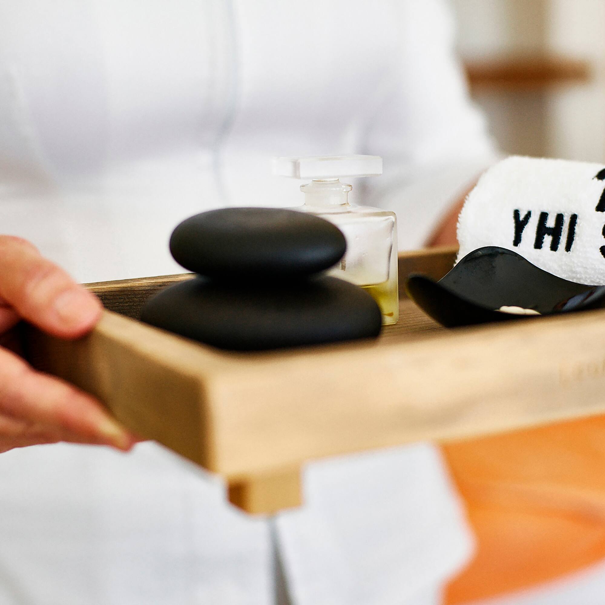 a person holding a tray of black stones