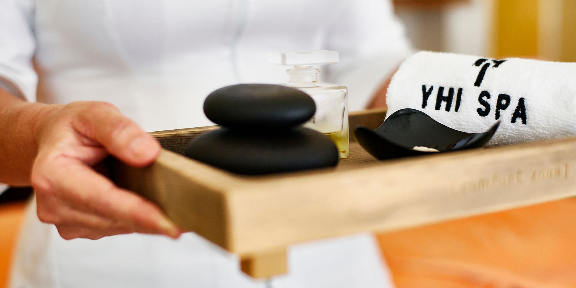 a person holding a tray of black stones