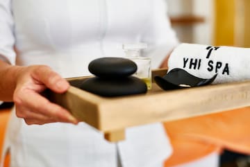 a person holding a tray of black stones