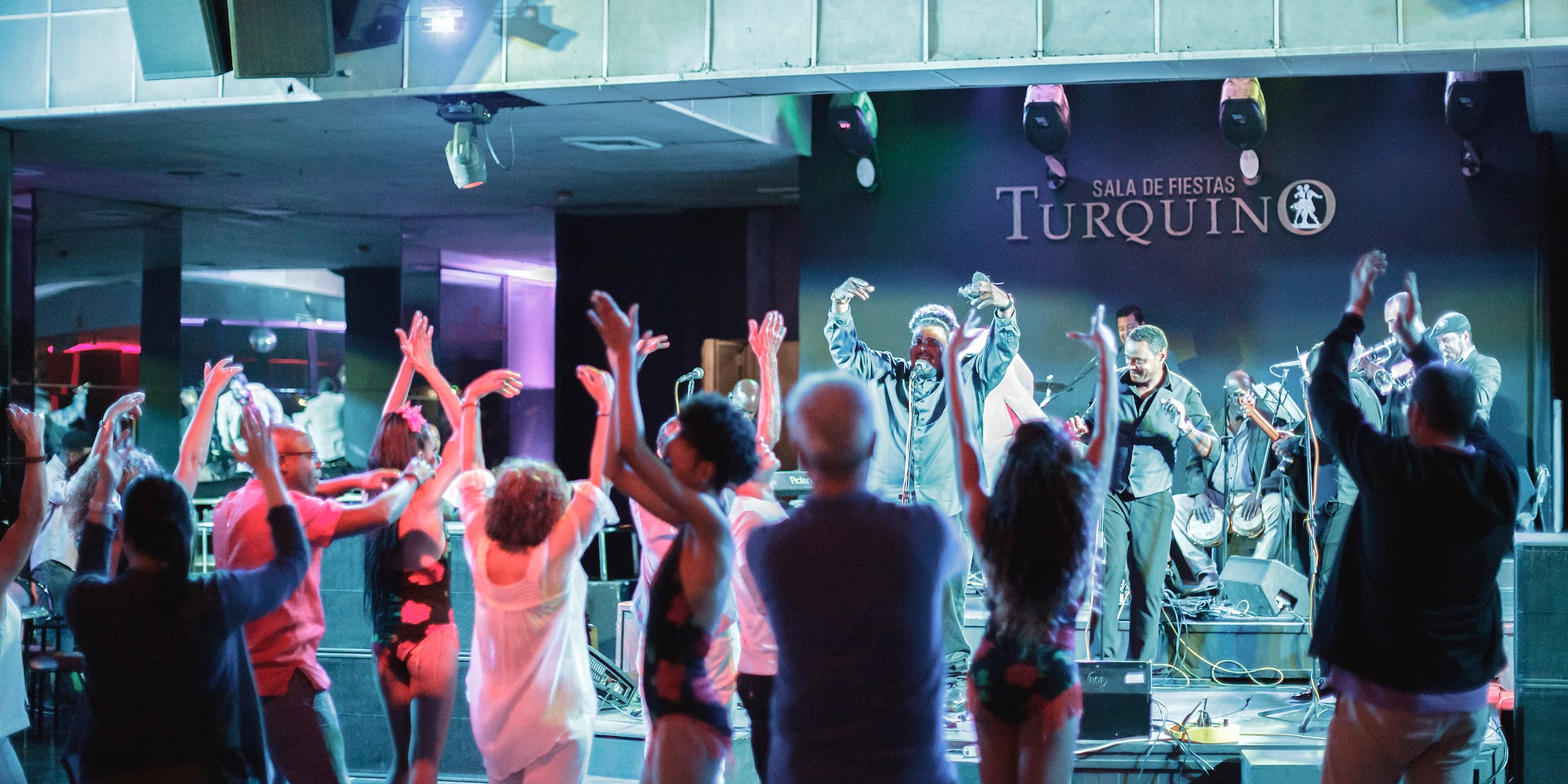 a group of people on a stage with a man on a stage with hands up