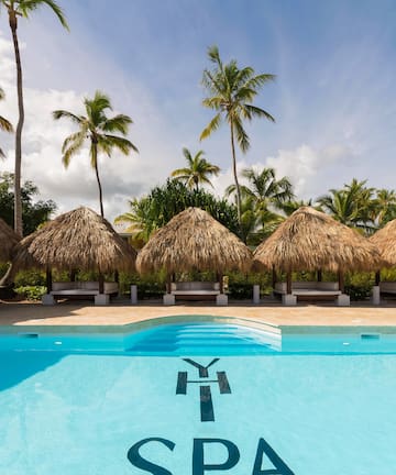 a pool with straw umbrellas and palm trees