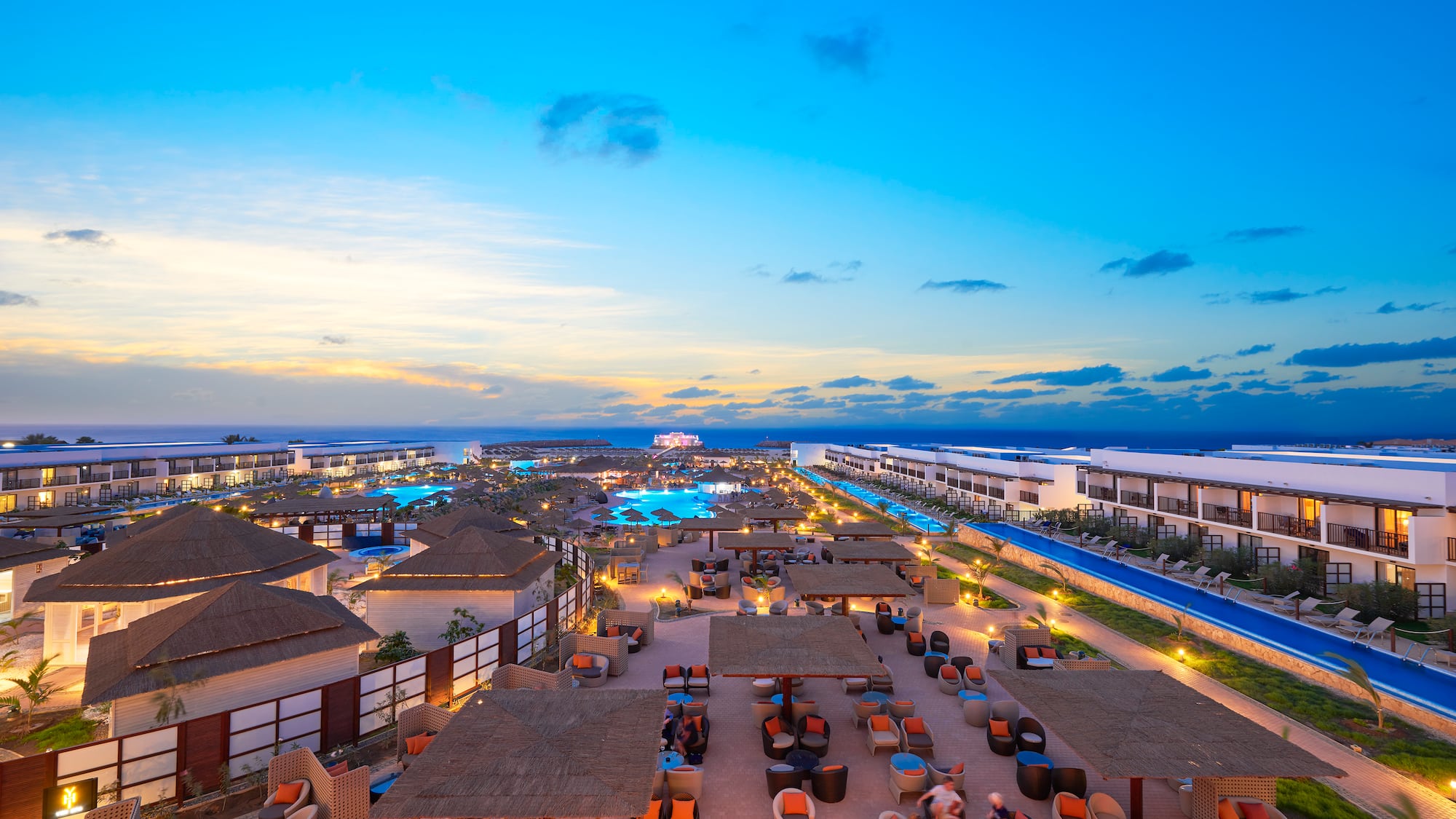 a group of buildings with chairs and tables in a resort
