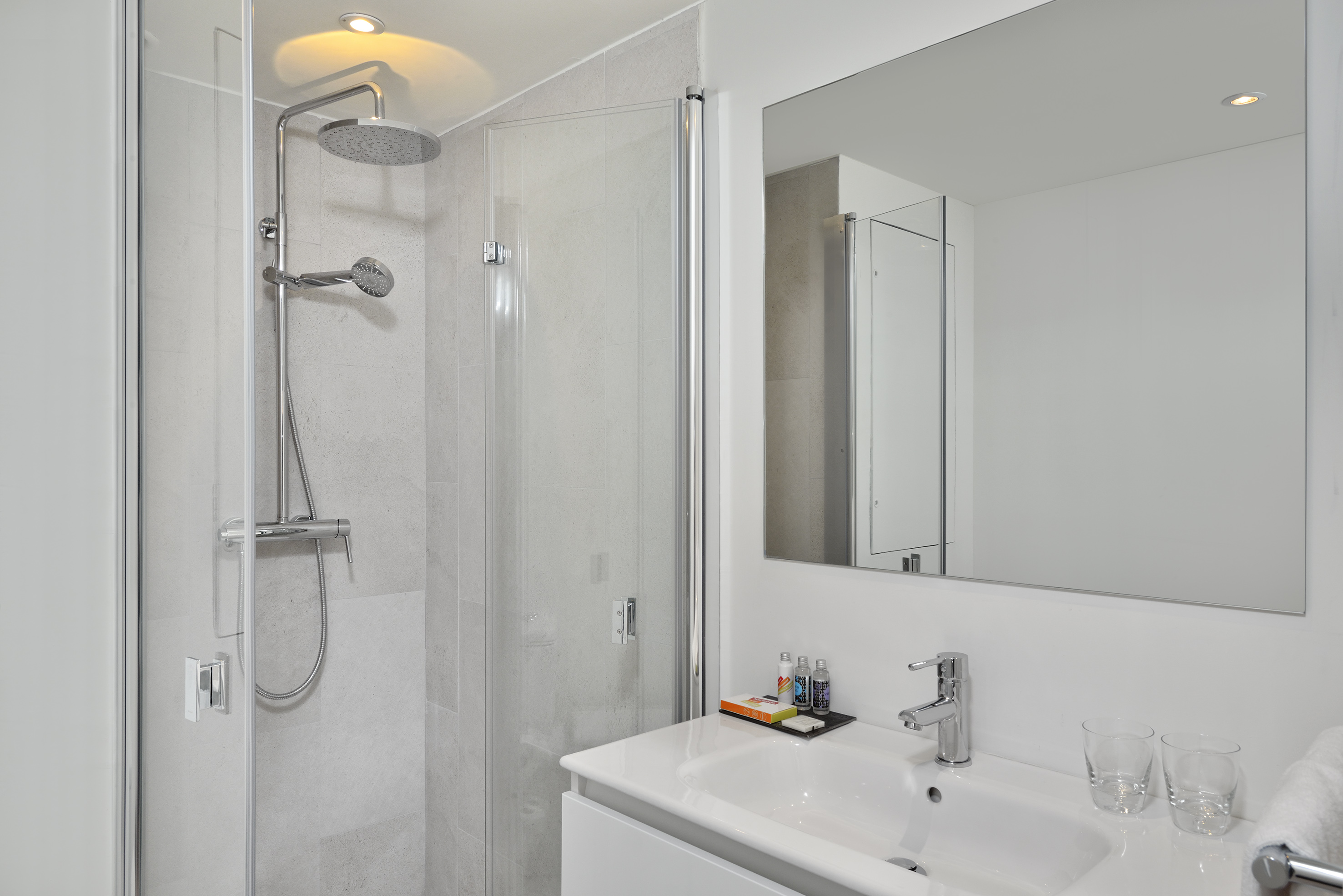 Clean, modern bathroom with glass-enclosed shower and white sink vanity.