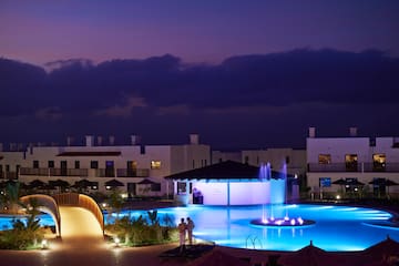 a pool with a fountain and buildings in the background
