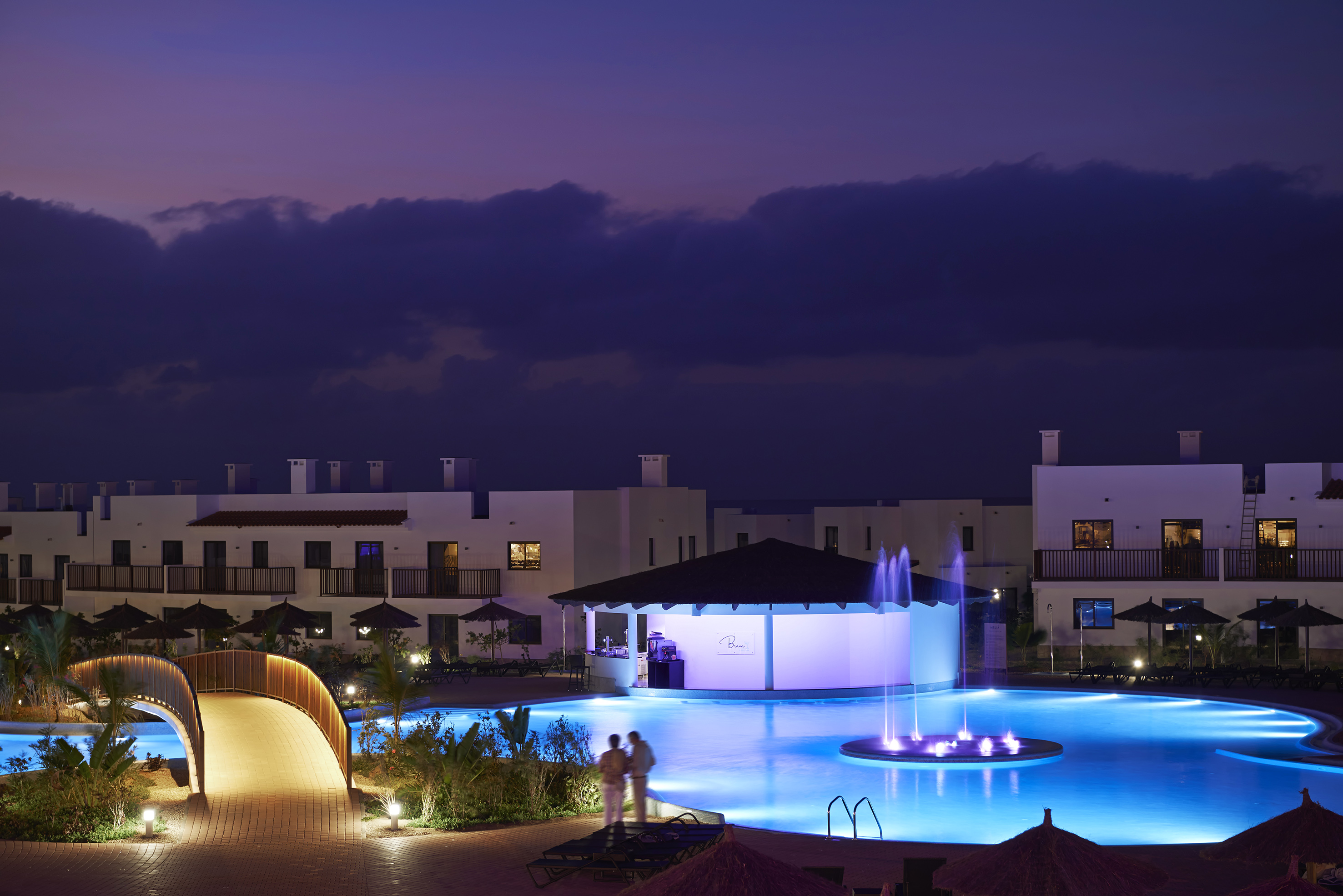 a pool with a fountain and buildings in the background