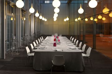 a long table with white chairs and plates