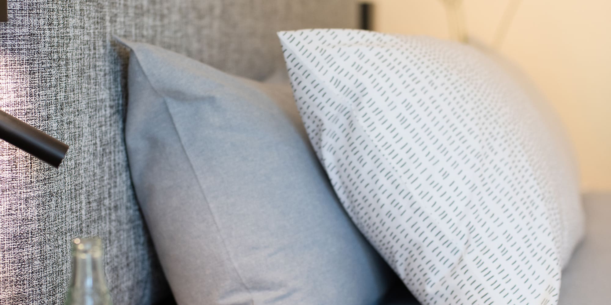 a bed with a telephone and a bottle of water on a table