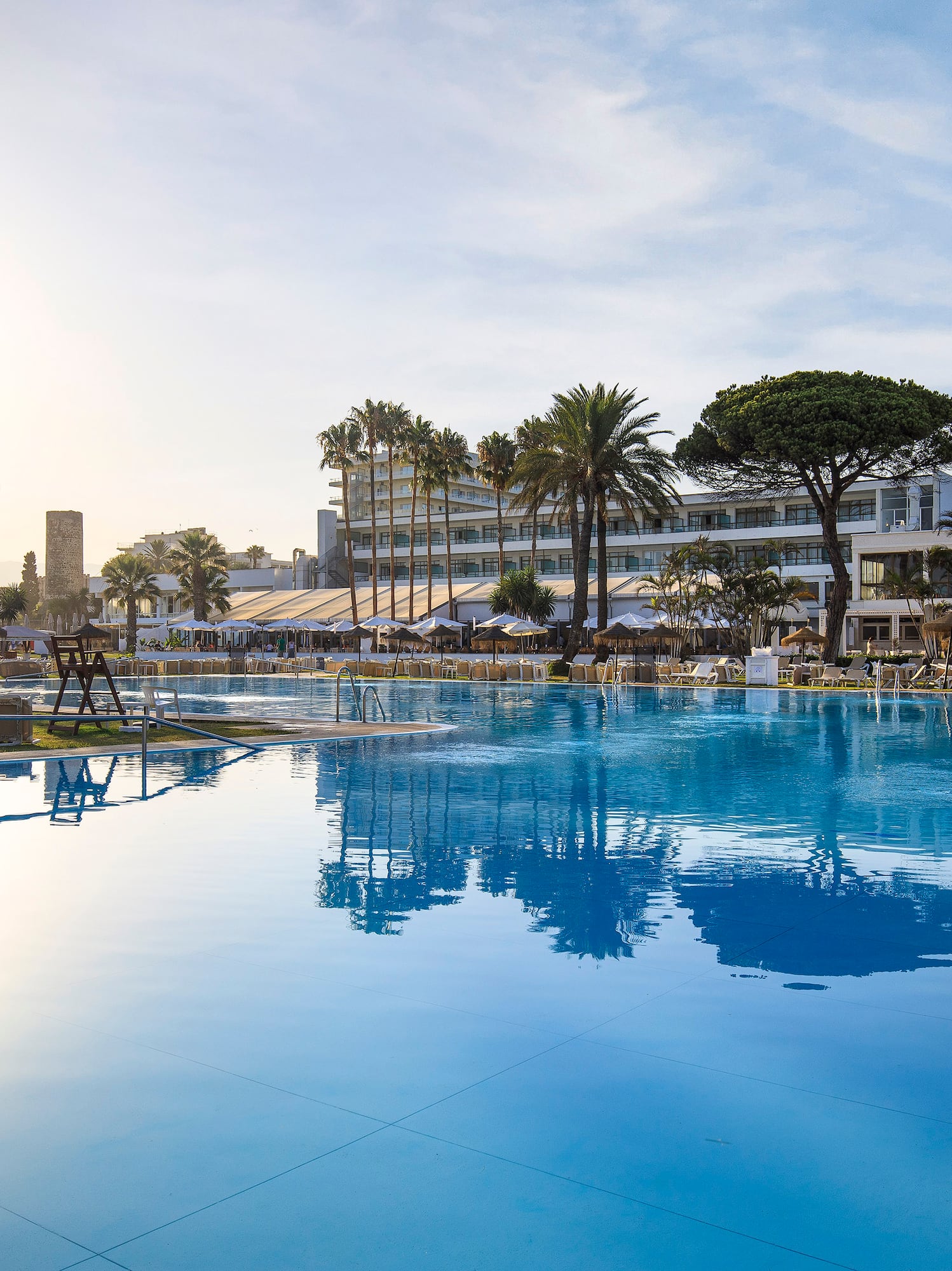 a pool with palm trees and buildings in the background