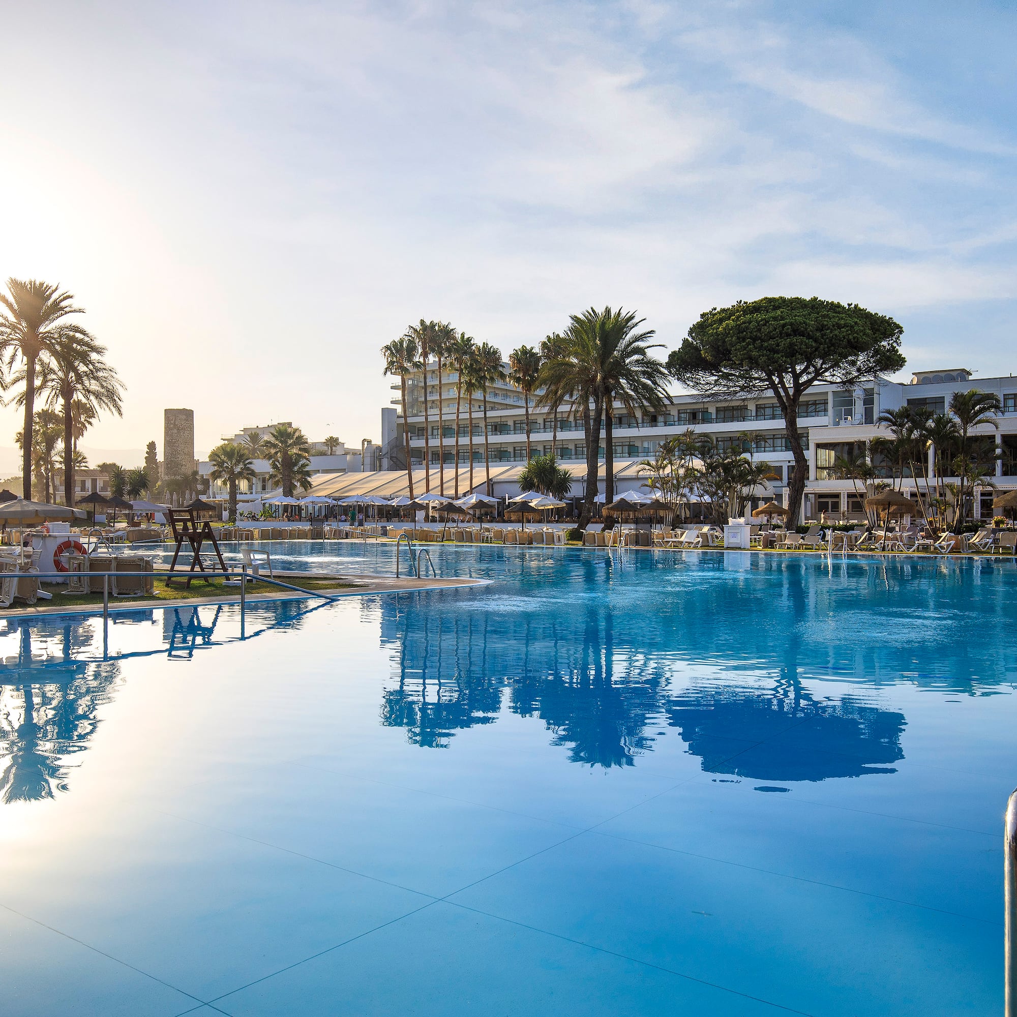 a pool with palm trees and buildings in the background