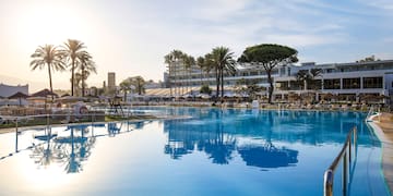 a pool with palm trees and buildings in the background