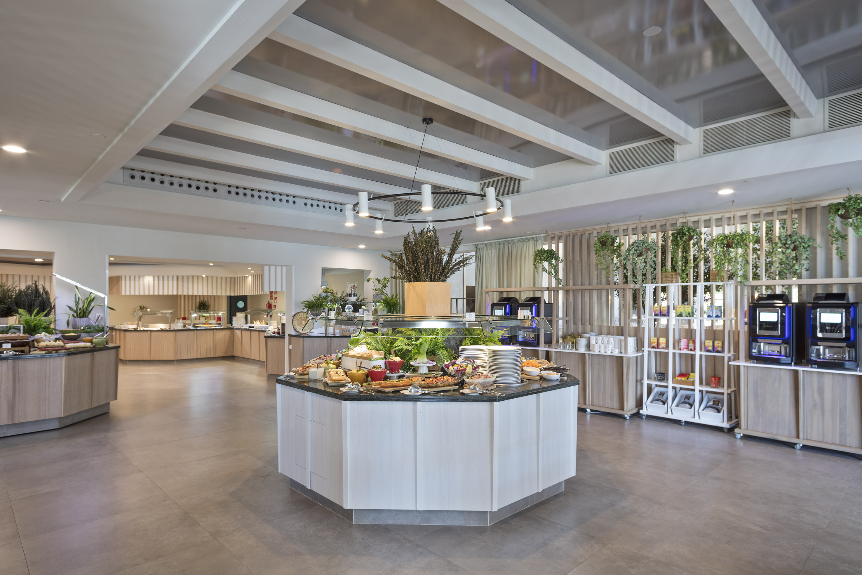 Modern hotel buffet with fresh food stations and beverage dispensers.