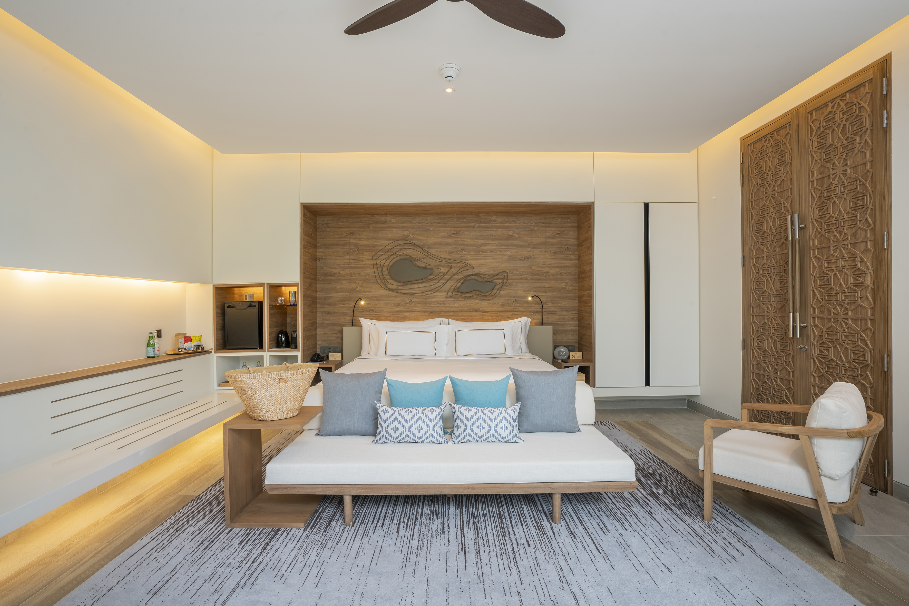 Modern luxury hotel room with king bed, wood features, and cozy daybed.