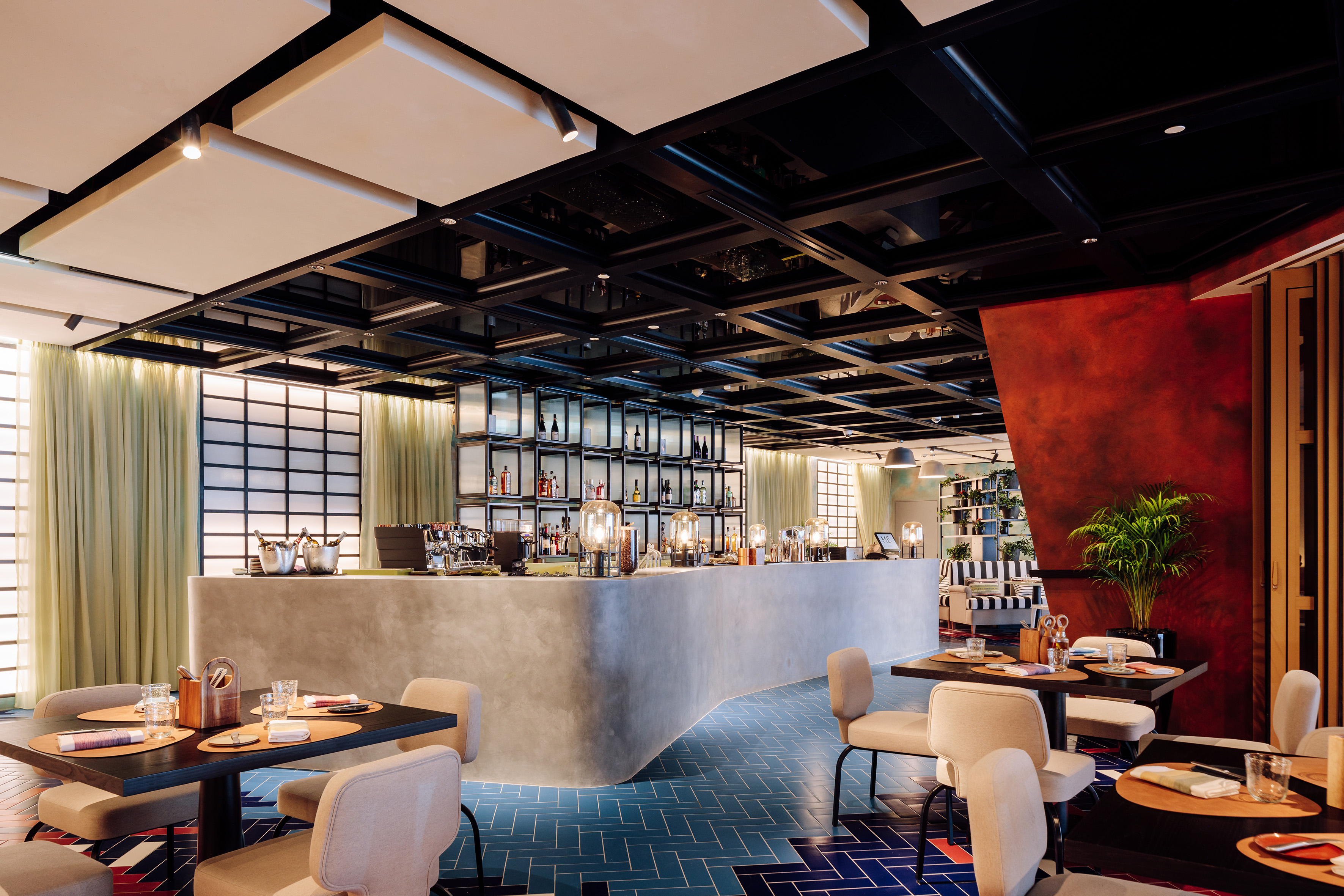 Modern restaurant and bar, concrete counter, blue tiled floor, dining tables.