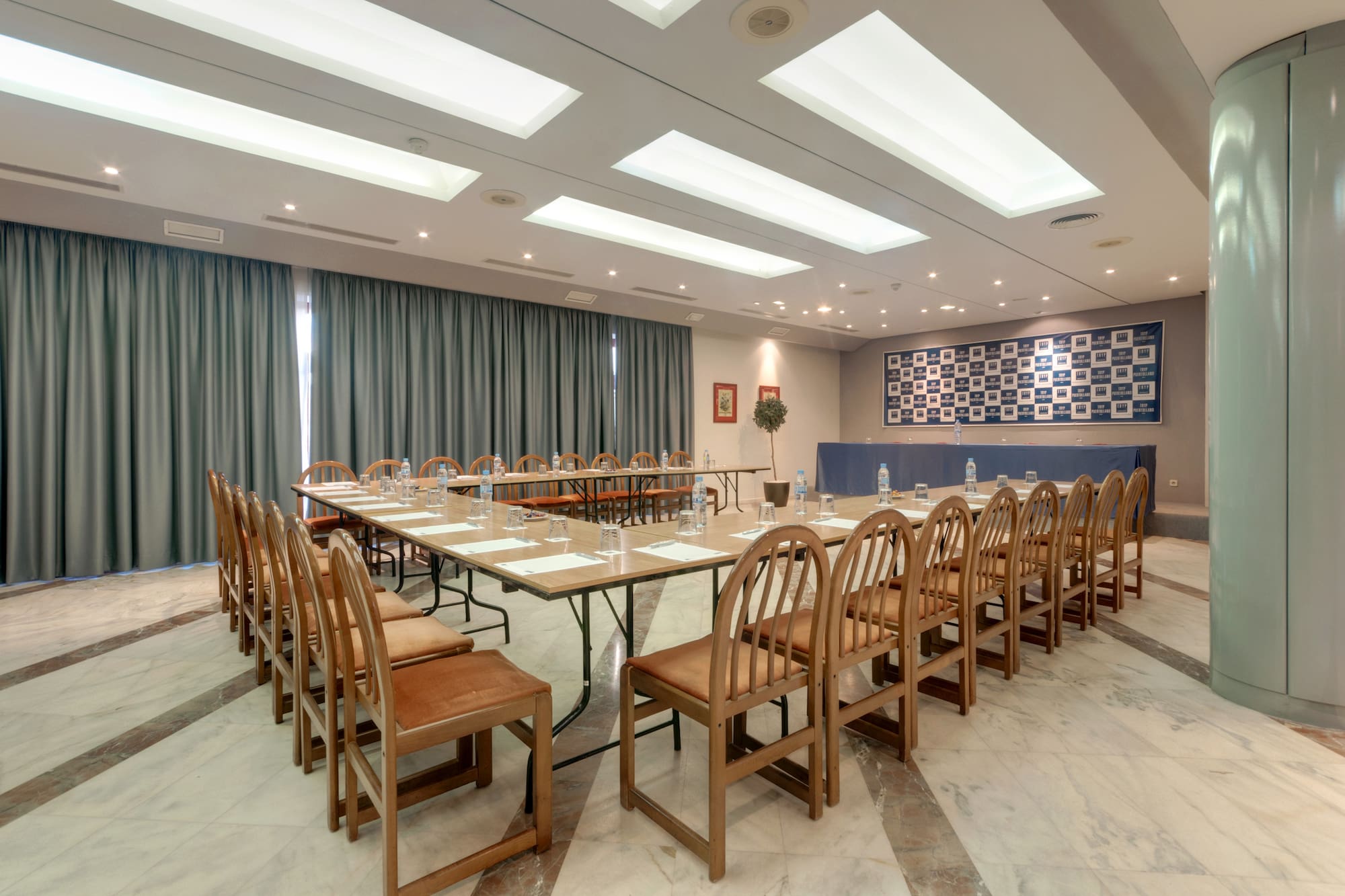 U-shaped corporate conference room with modern lighting, tables, and chairs, ready for events.