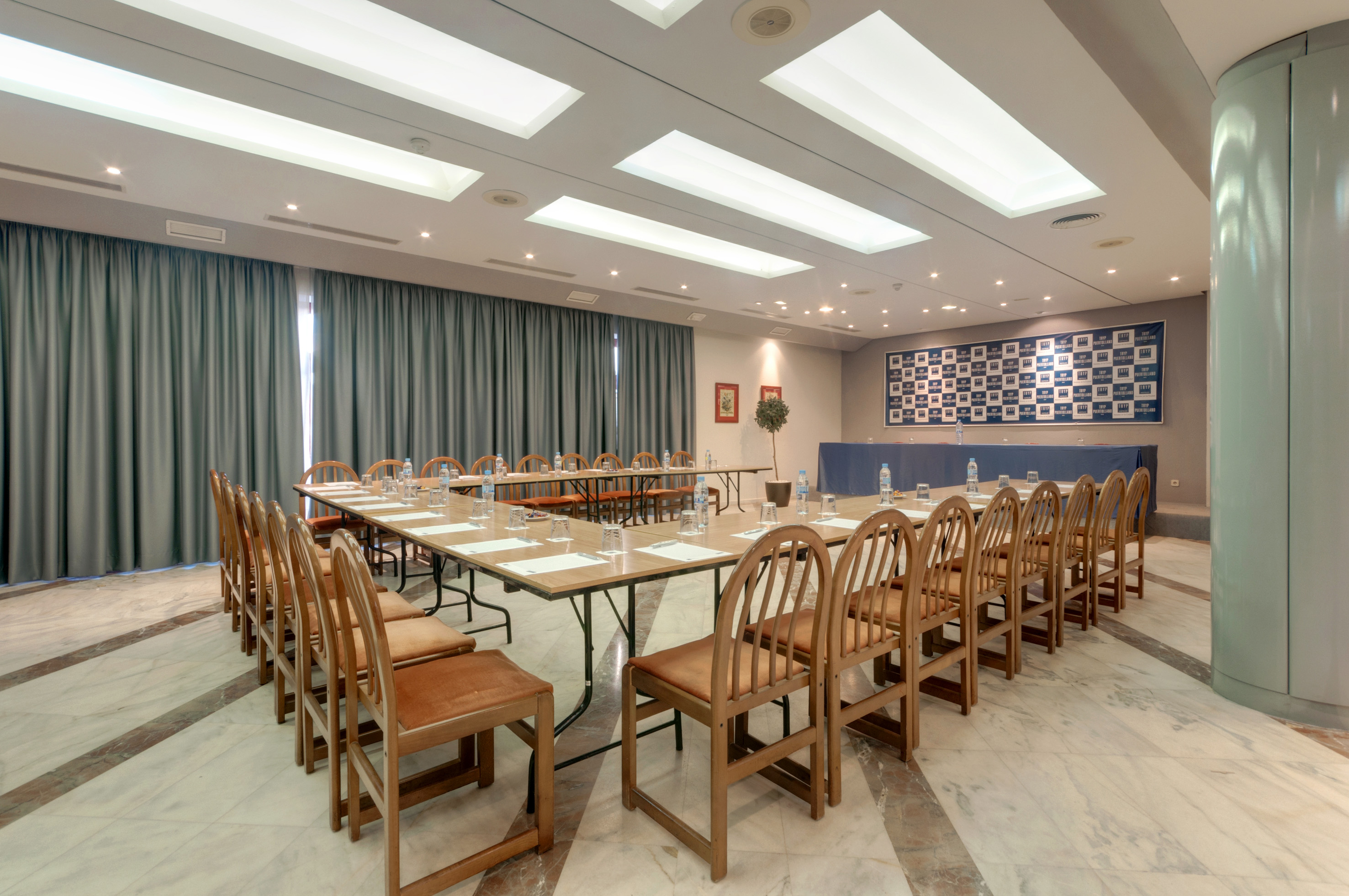 U-shaped corporate conference room with modern lighting, tables, and chairs, ready for events.