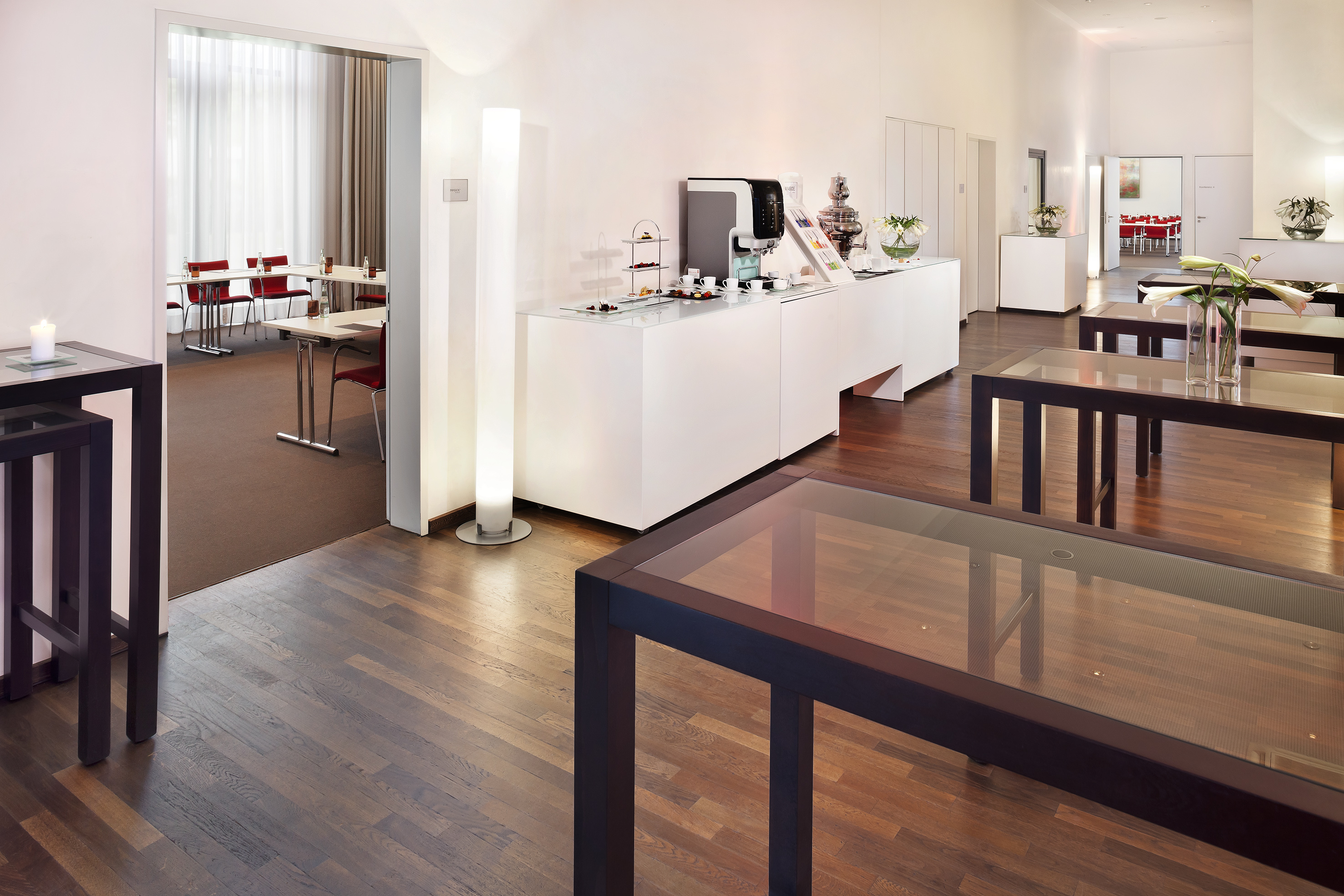 Modern event space with coffee break buffet, reception tables, and meeting room.