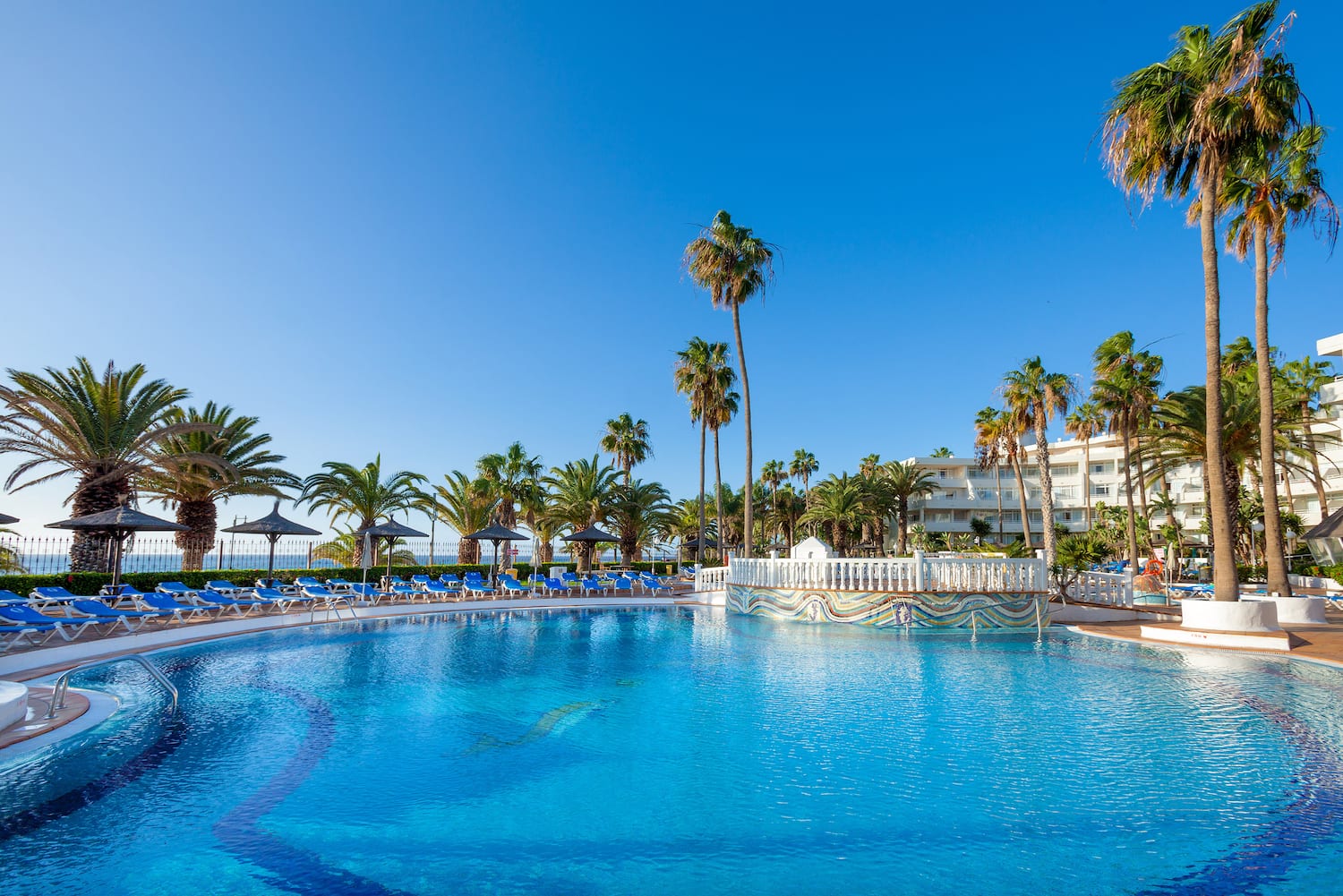 a pool with palm trees and a building