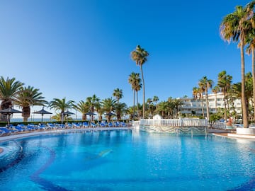 a pool with palm trees and a building