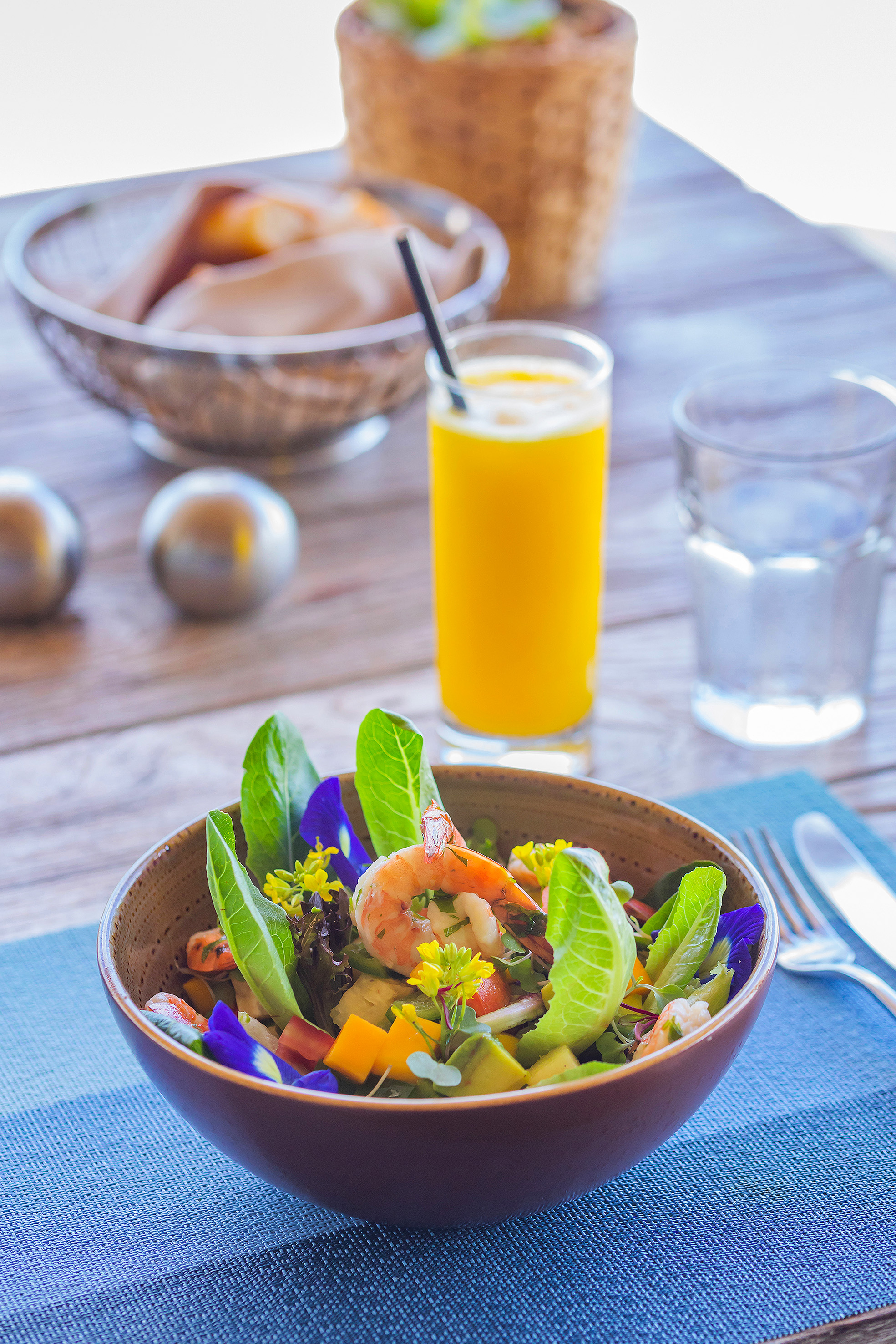 Colorful shrimp salad with mango, avocado, butterfly pea flowers, and juice.