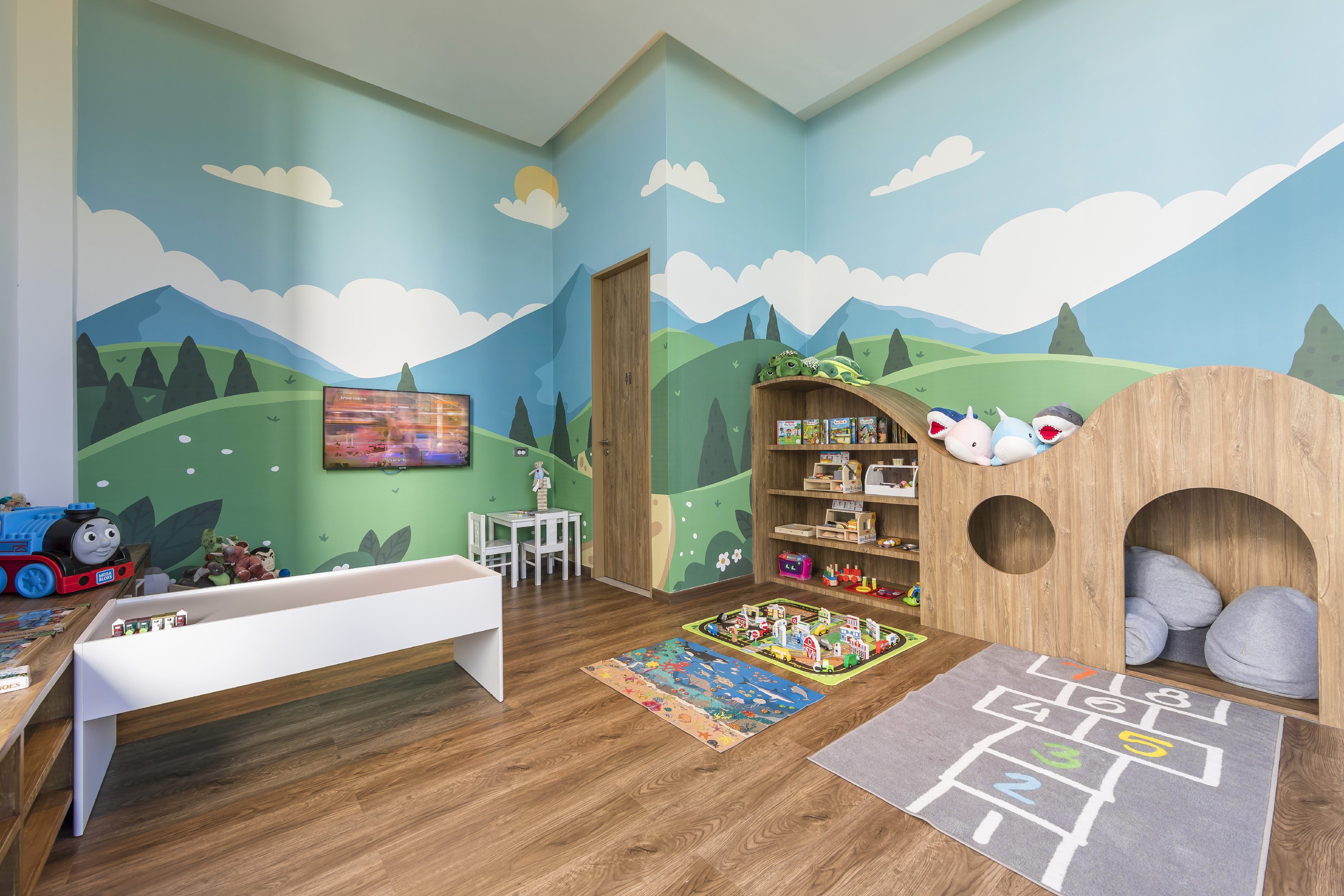 Colorful children's playroom with mountain mural, wooden play area, and toys.