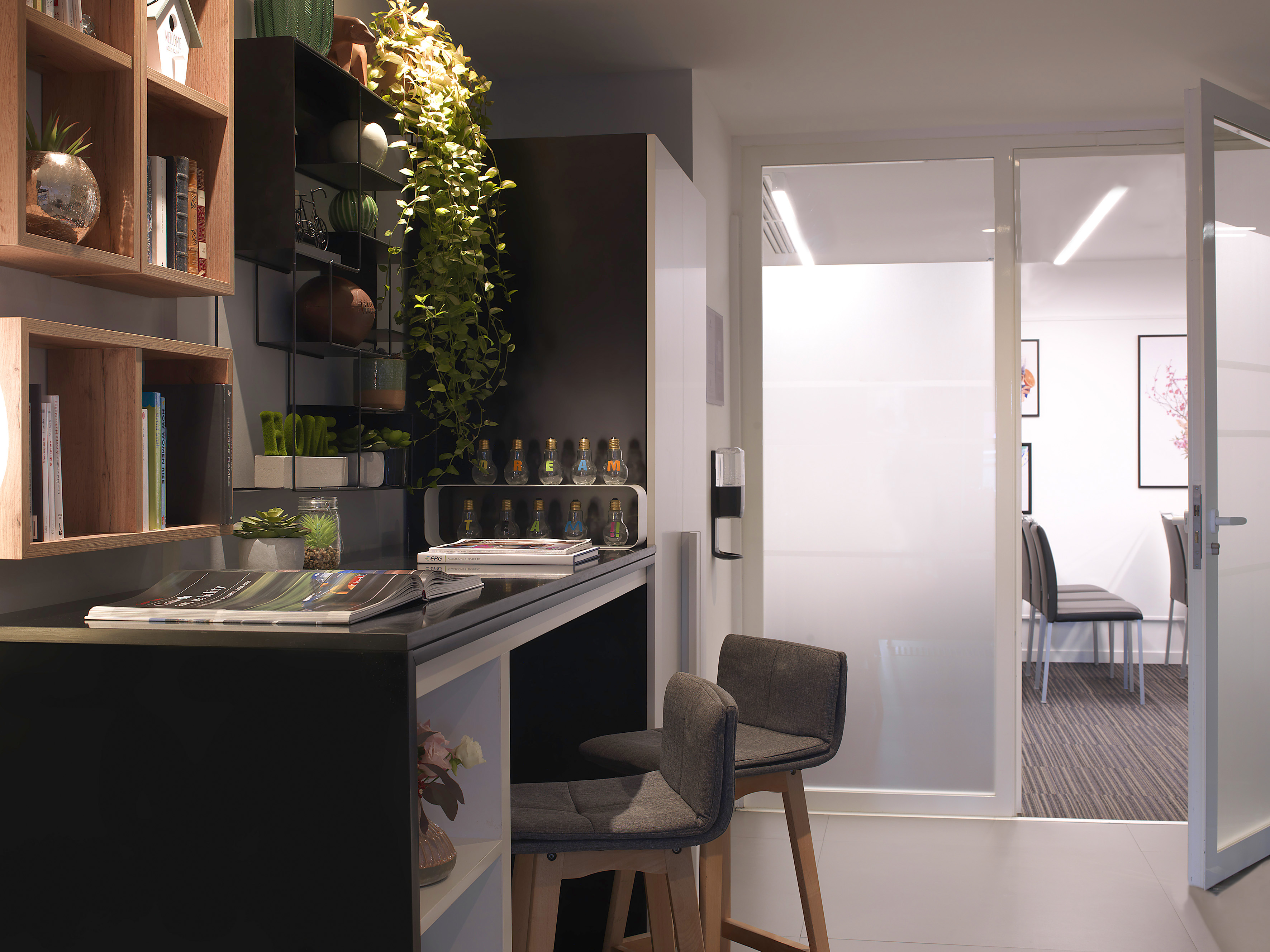 Modern office desk with bar stools, shelves, plants, and glass partition.