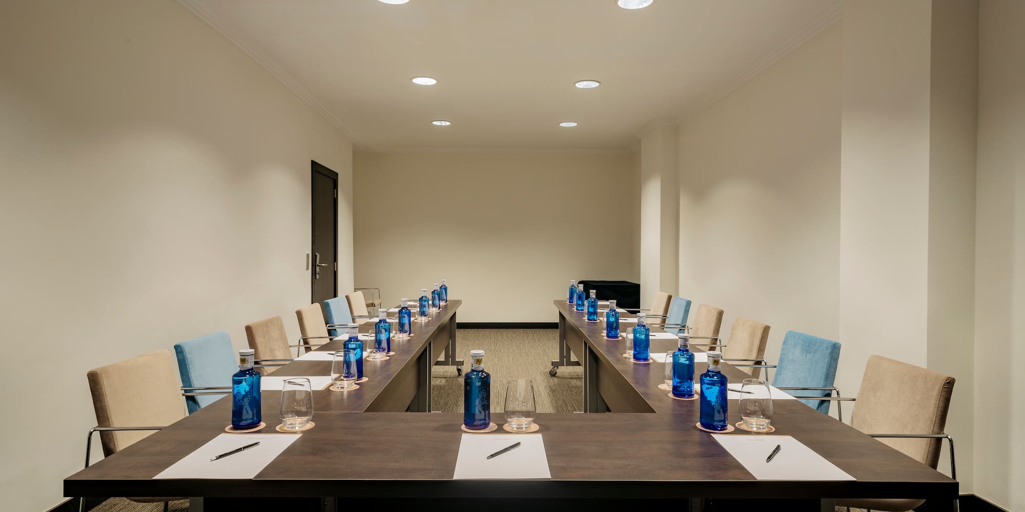 a room with a long table with blue bottles and pens