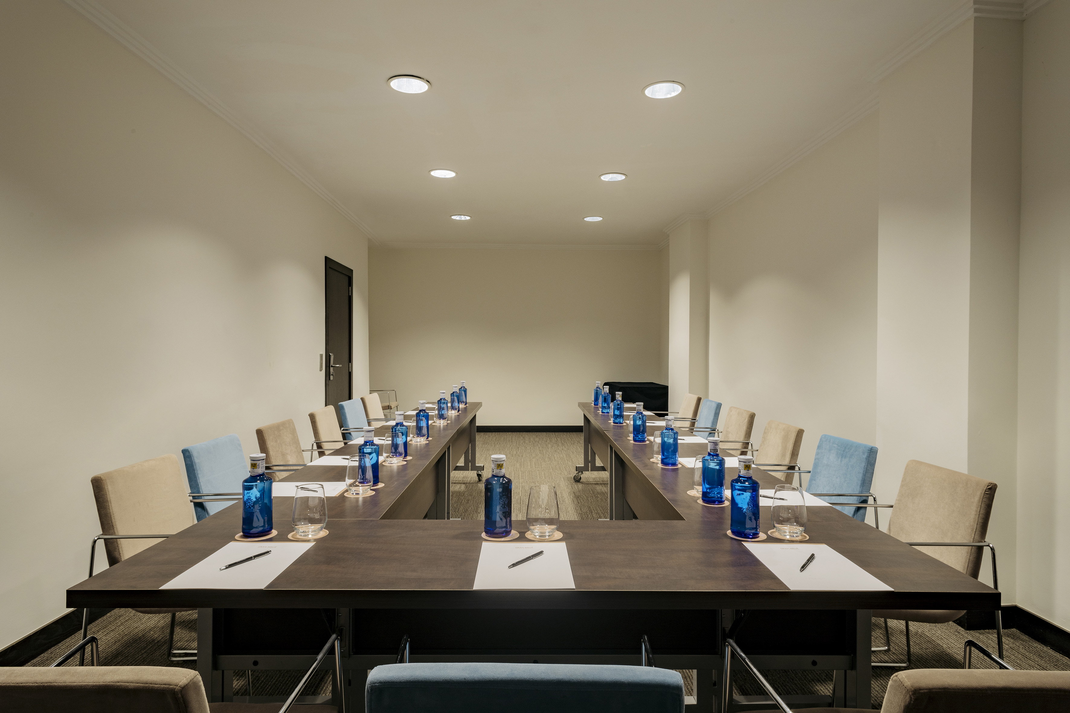a room with a long table with blue bottles and pens