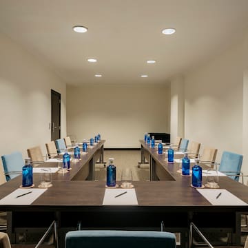 a room with a long table with blue bottles and pens