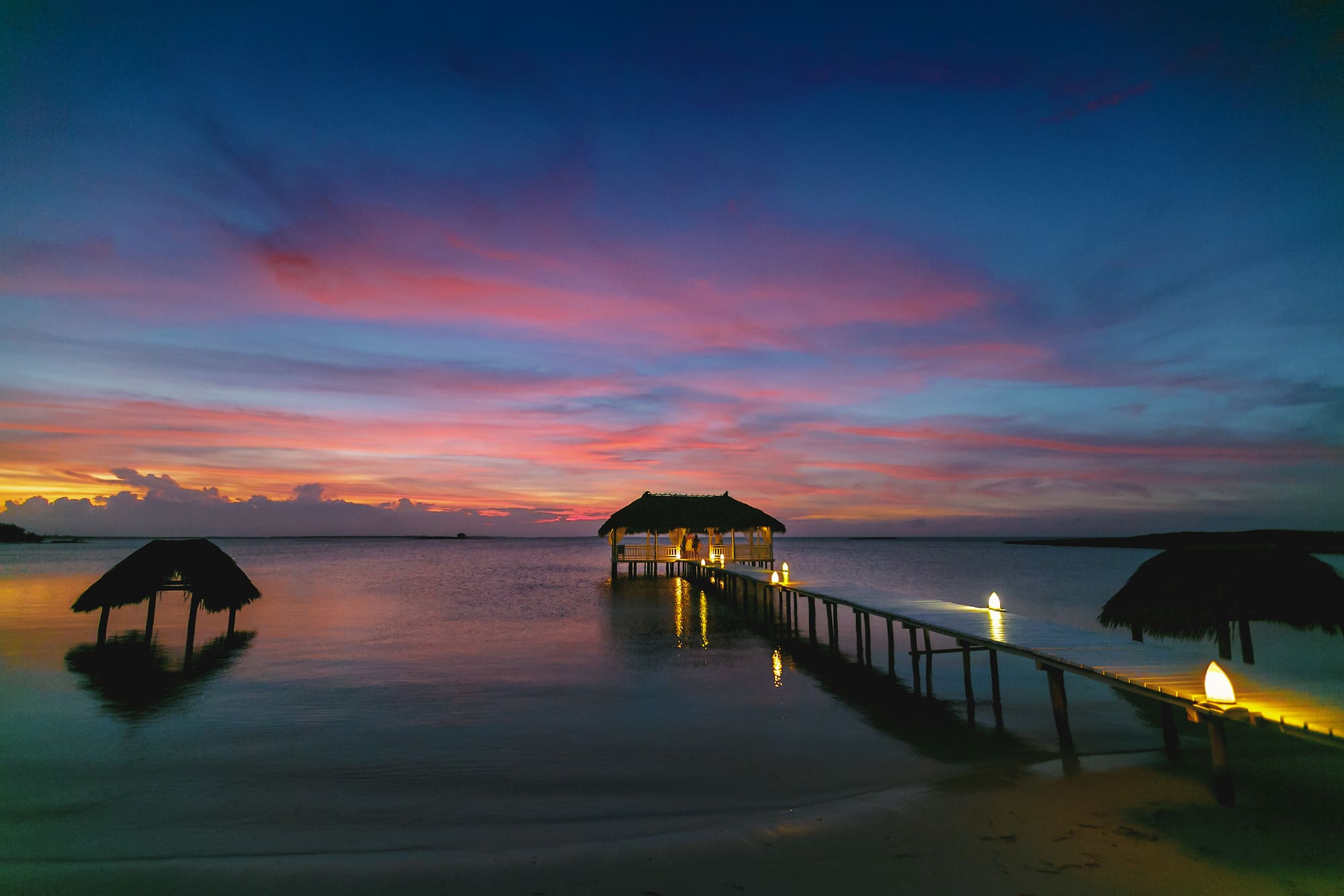 a dock with a thatched roof and a thatched roof on the water