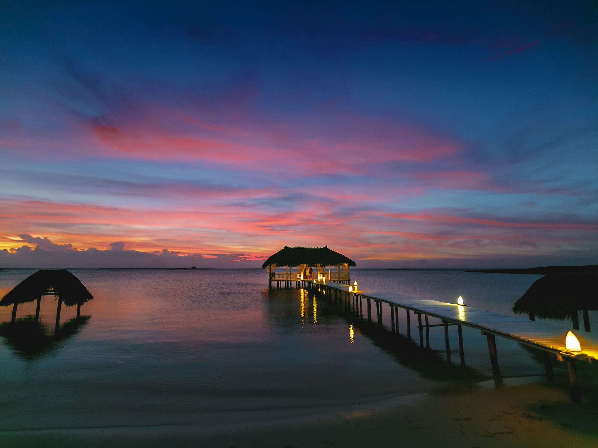a dock with a thatched roof and a thatched roof on the water