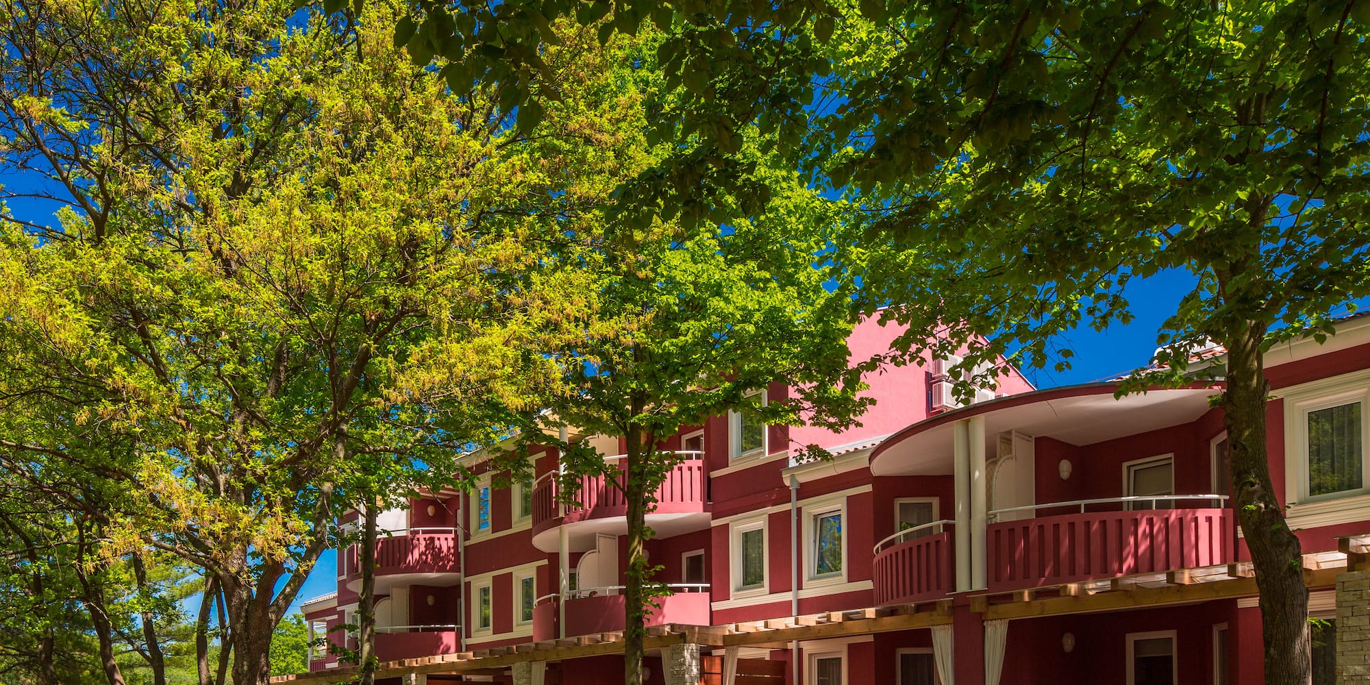 a row of red buildings with trees