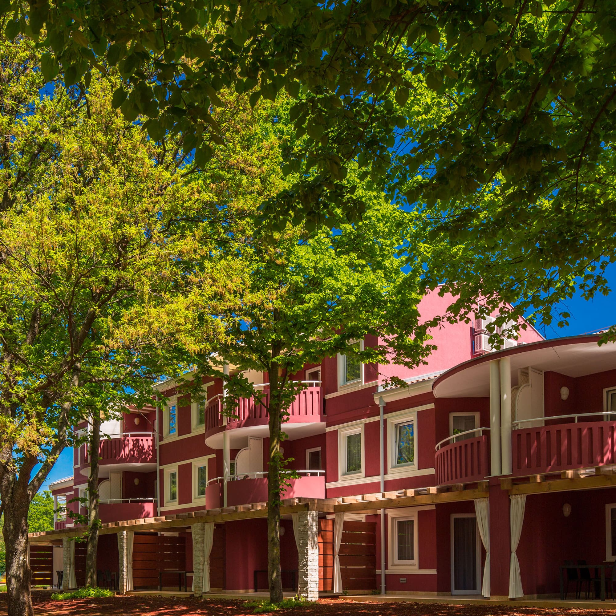 a row of red buildings with trees