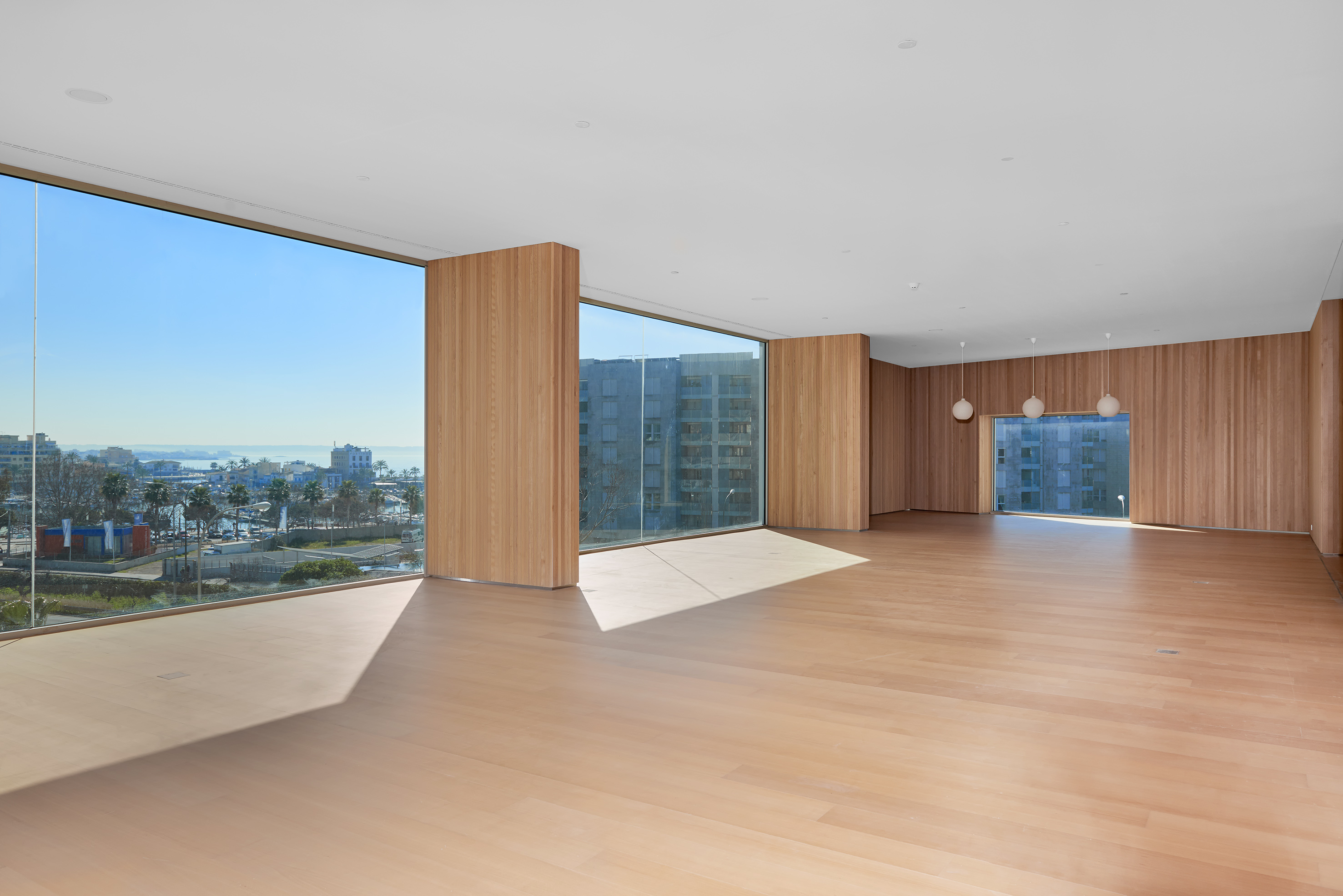 Modern empty room with floor-to-ceiling windows and panoramic city views.