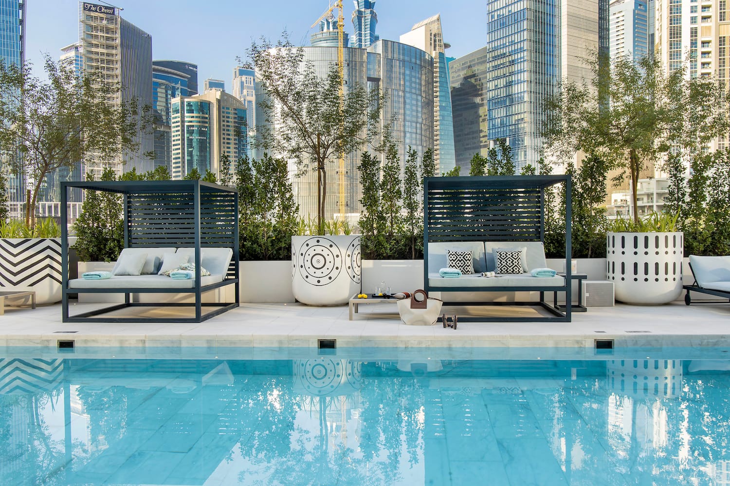 a pool with a couple of beds and a city skyline