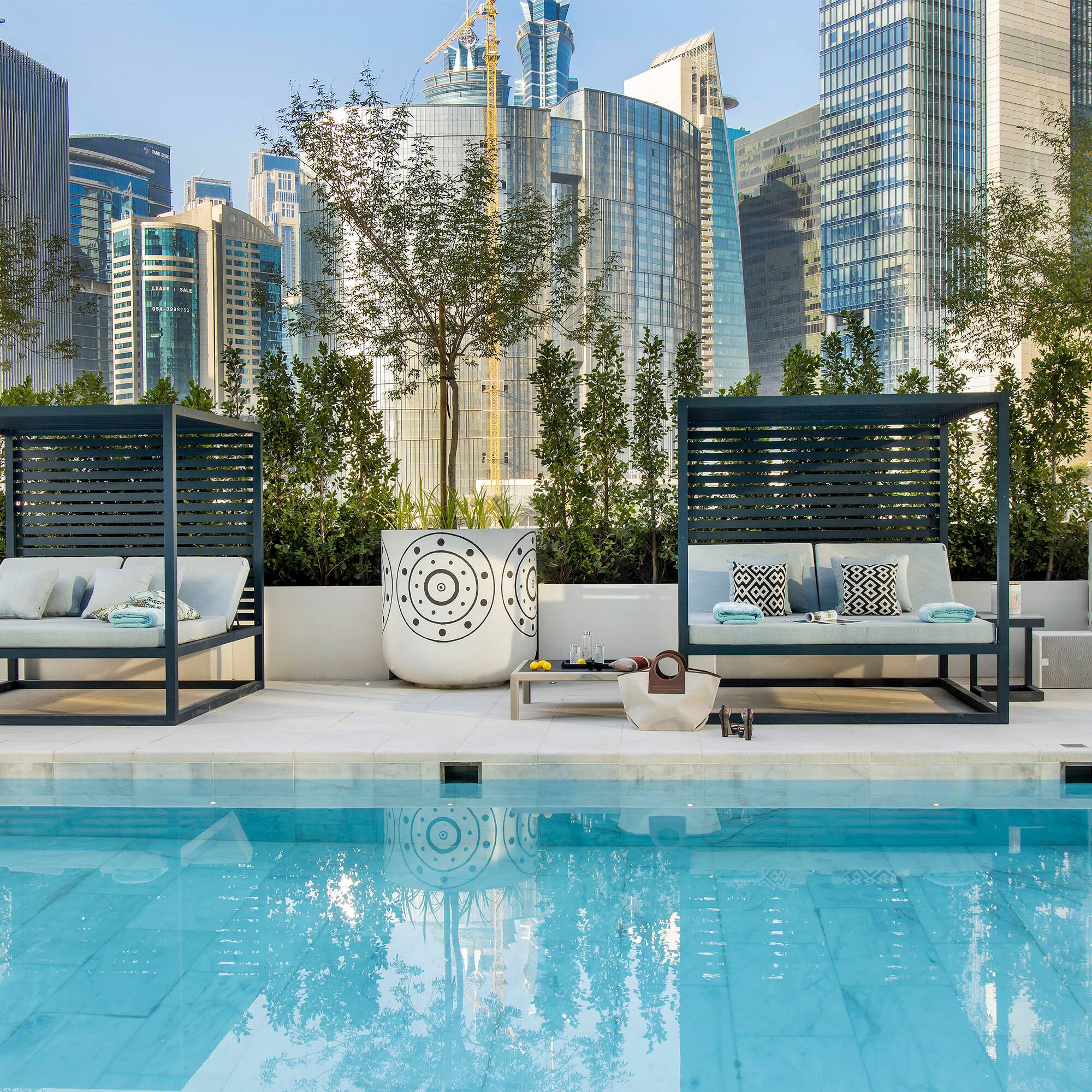 a pool with a couple of beds and a city skyline