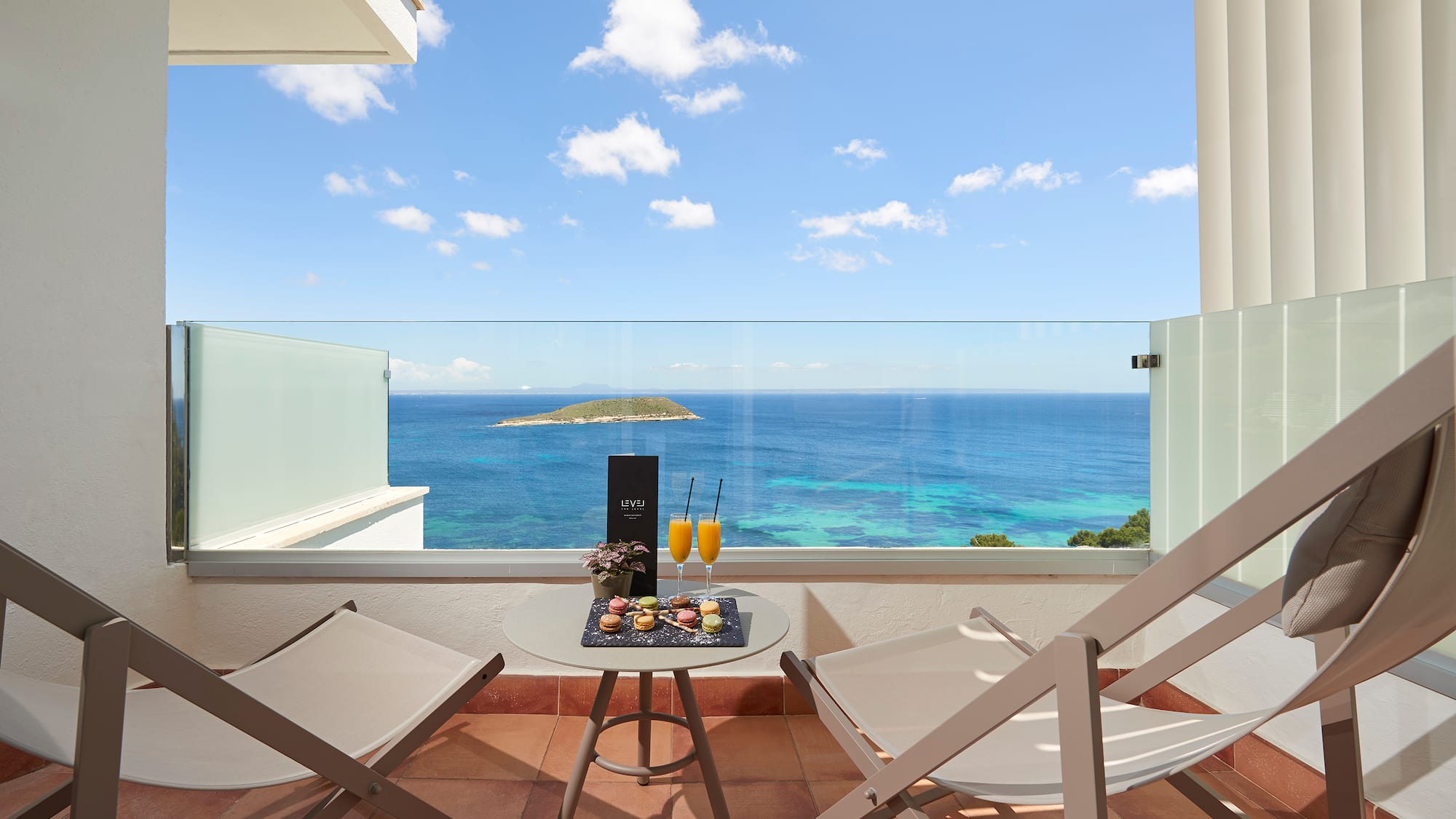 a table with drinks on it and chairs on a balcony overlooking the ocean