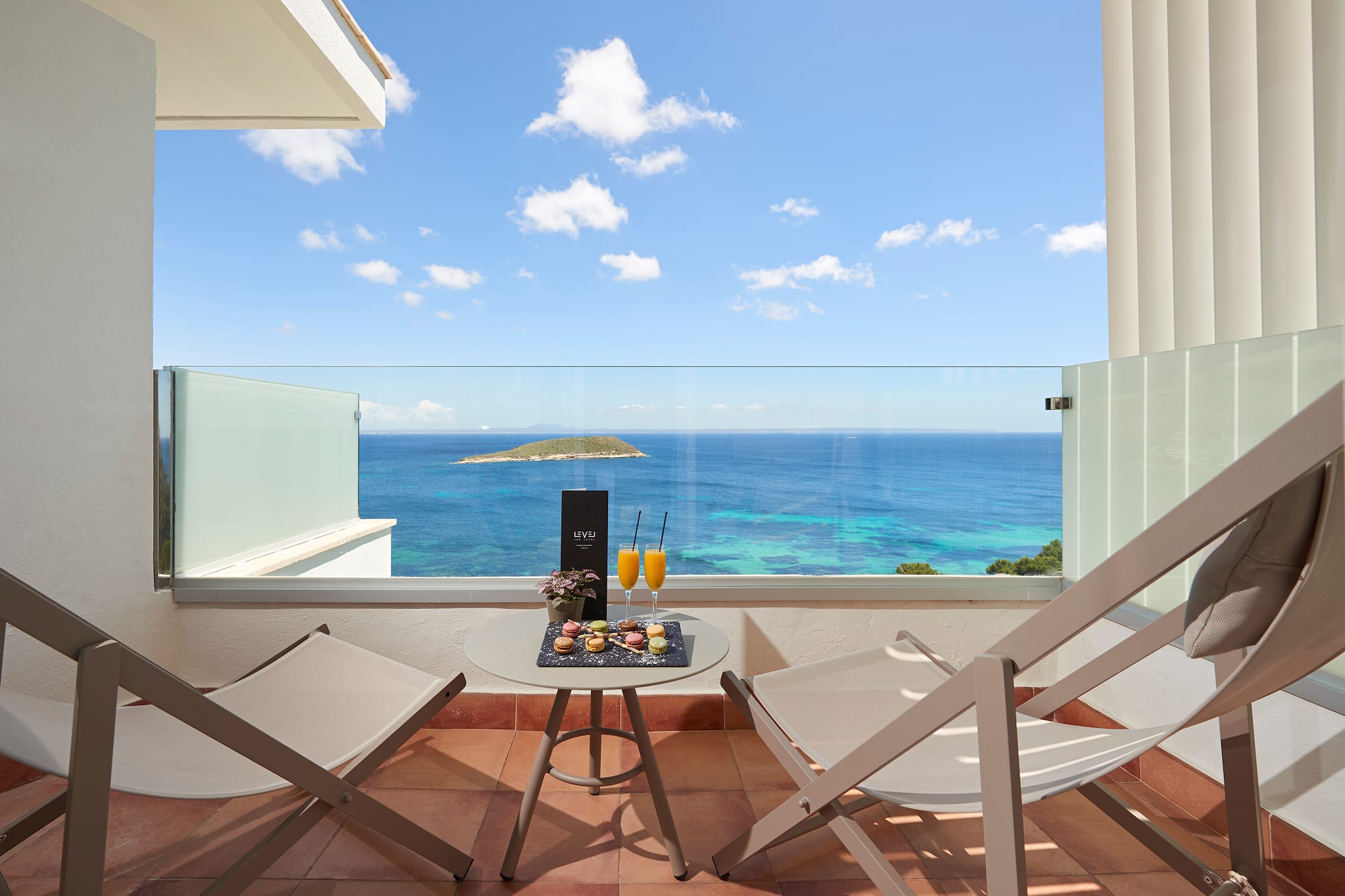 a table with drinks on it and chairs on a balcony overlooking the ocean