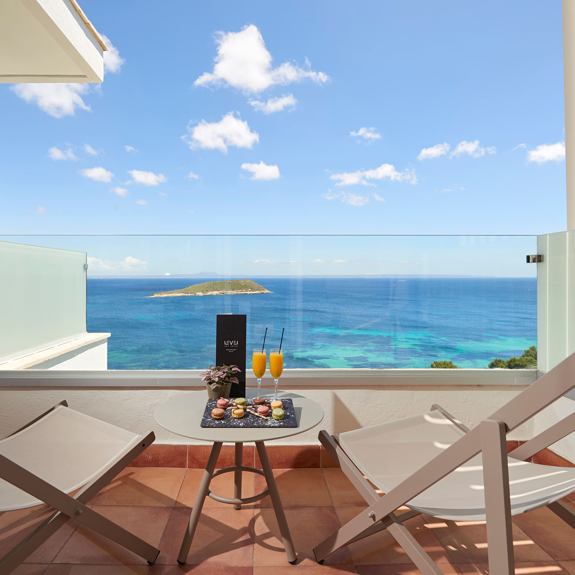 a table with drinks on it and chairs on a balcony overlooking the ocean