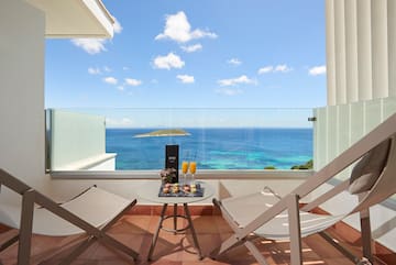 a table with drinks on it and chairs on a balcony overlooking the ocean