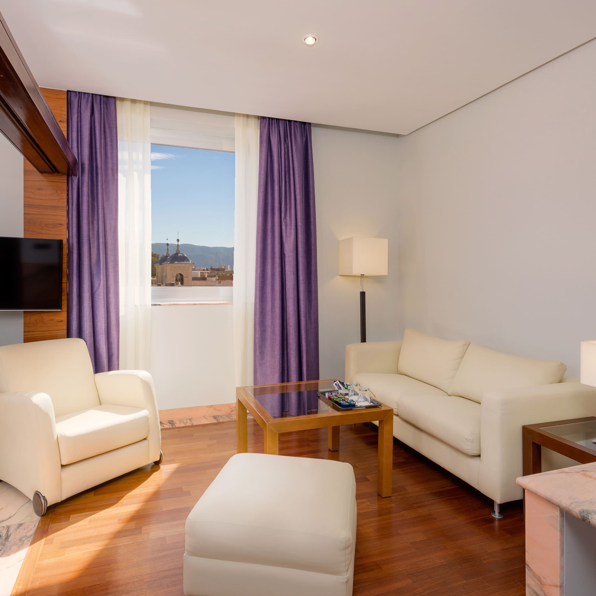 a living room with purple curtains and white furniture