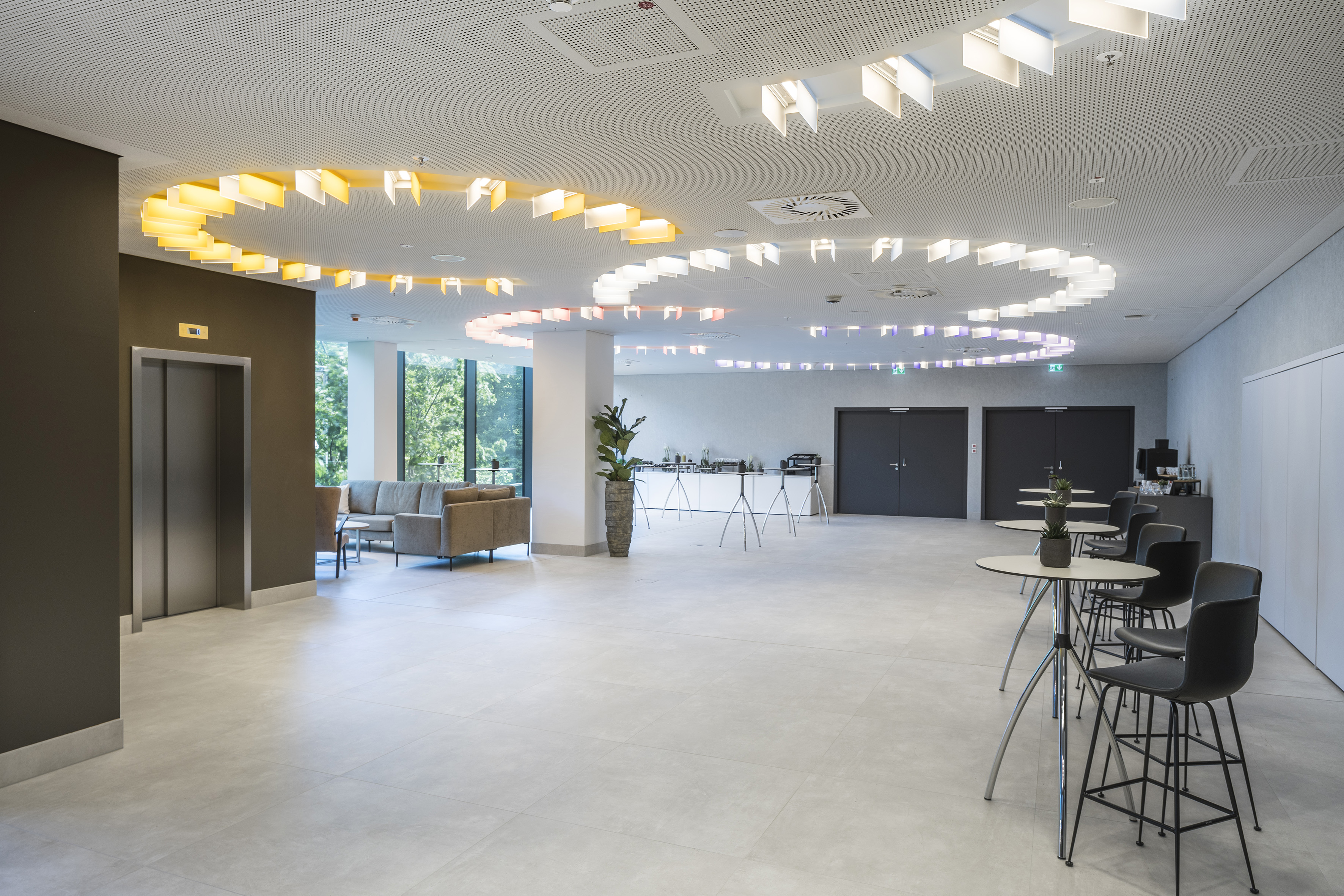 Modern hotel lobby lounge with unique wavy ceiling lights and bar tables.