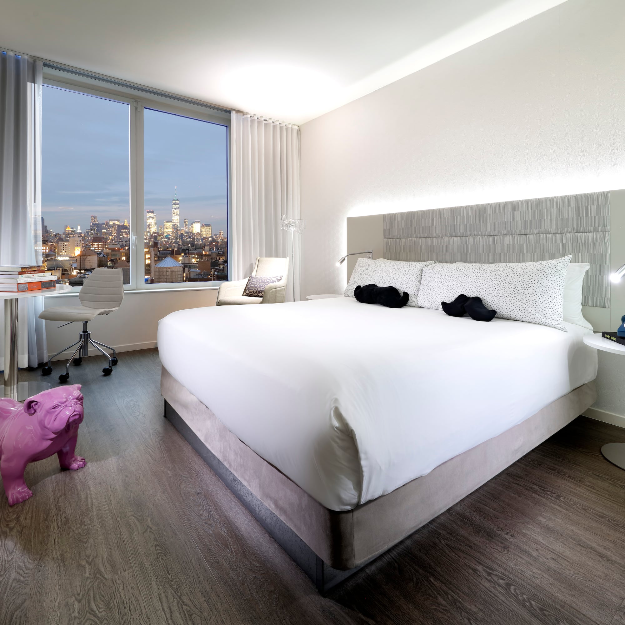 a bedroom with a large bed and a pink dog statue