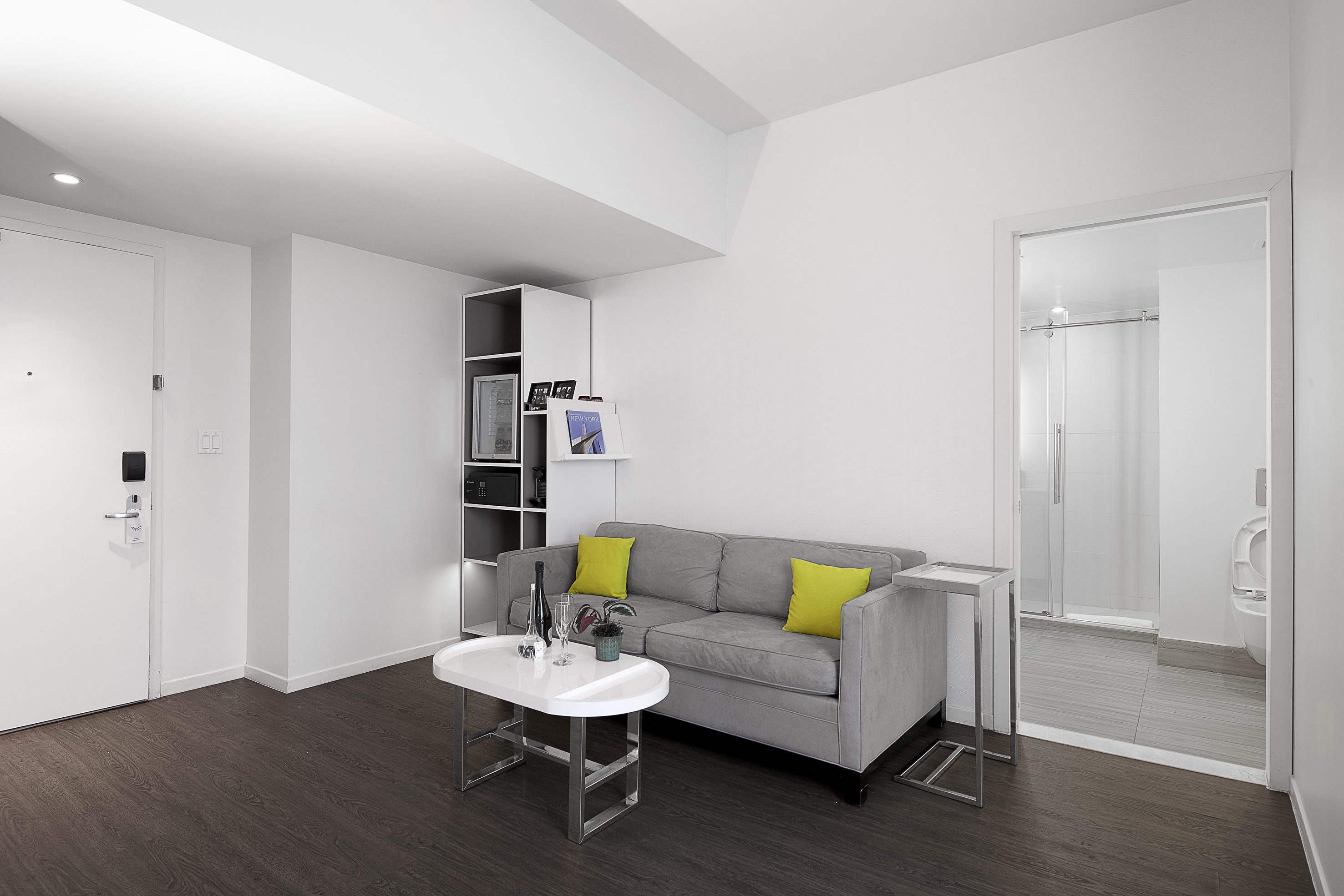 Modern studio living room with grey sofa, white table, and dark wood floor.