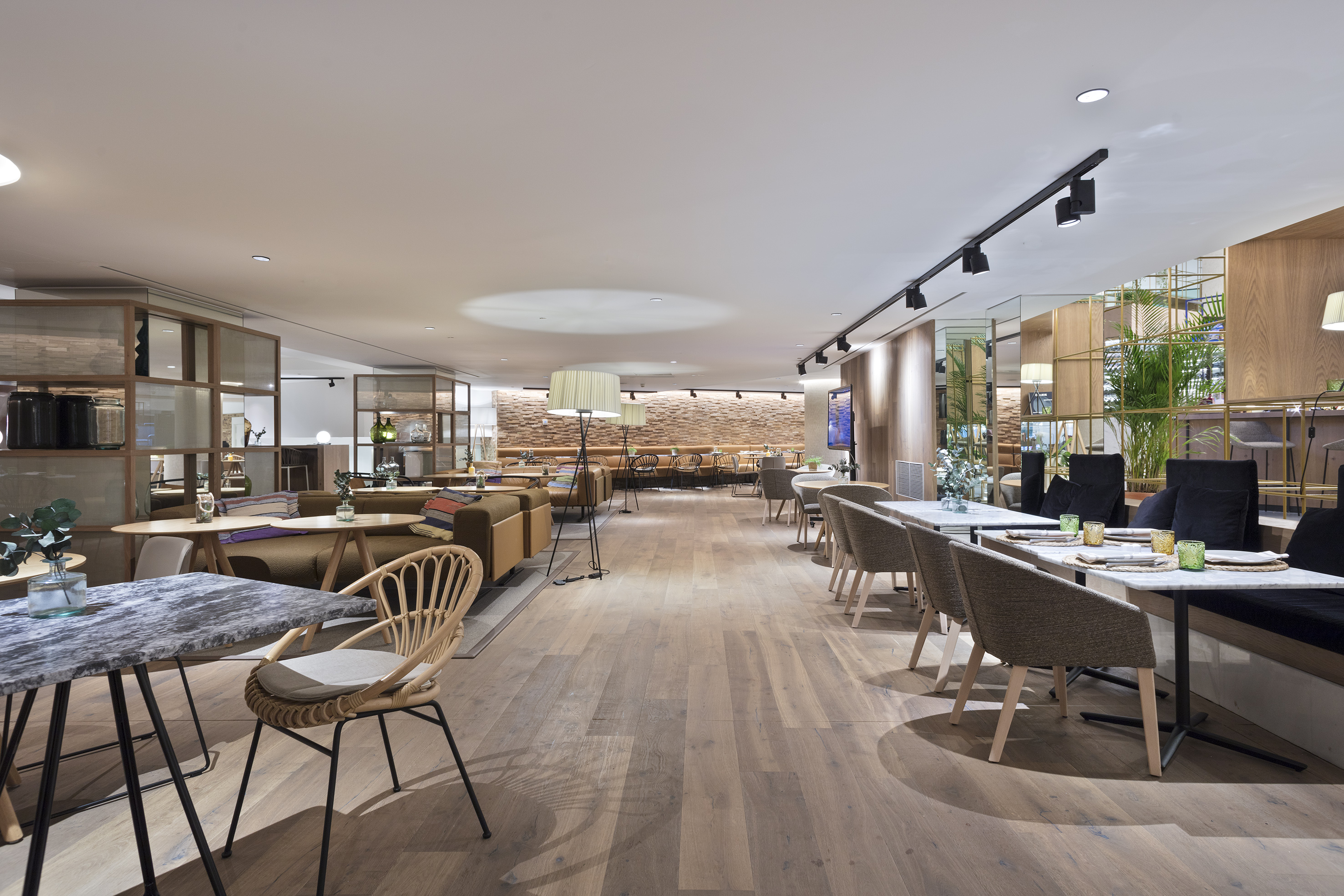 Modern restaurant interior with diverse seating, wood floor, and stylish decor.