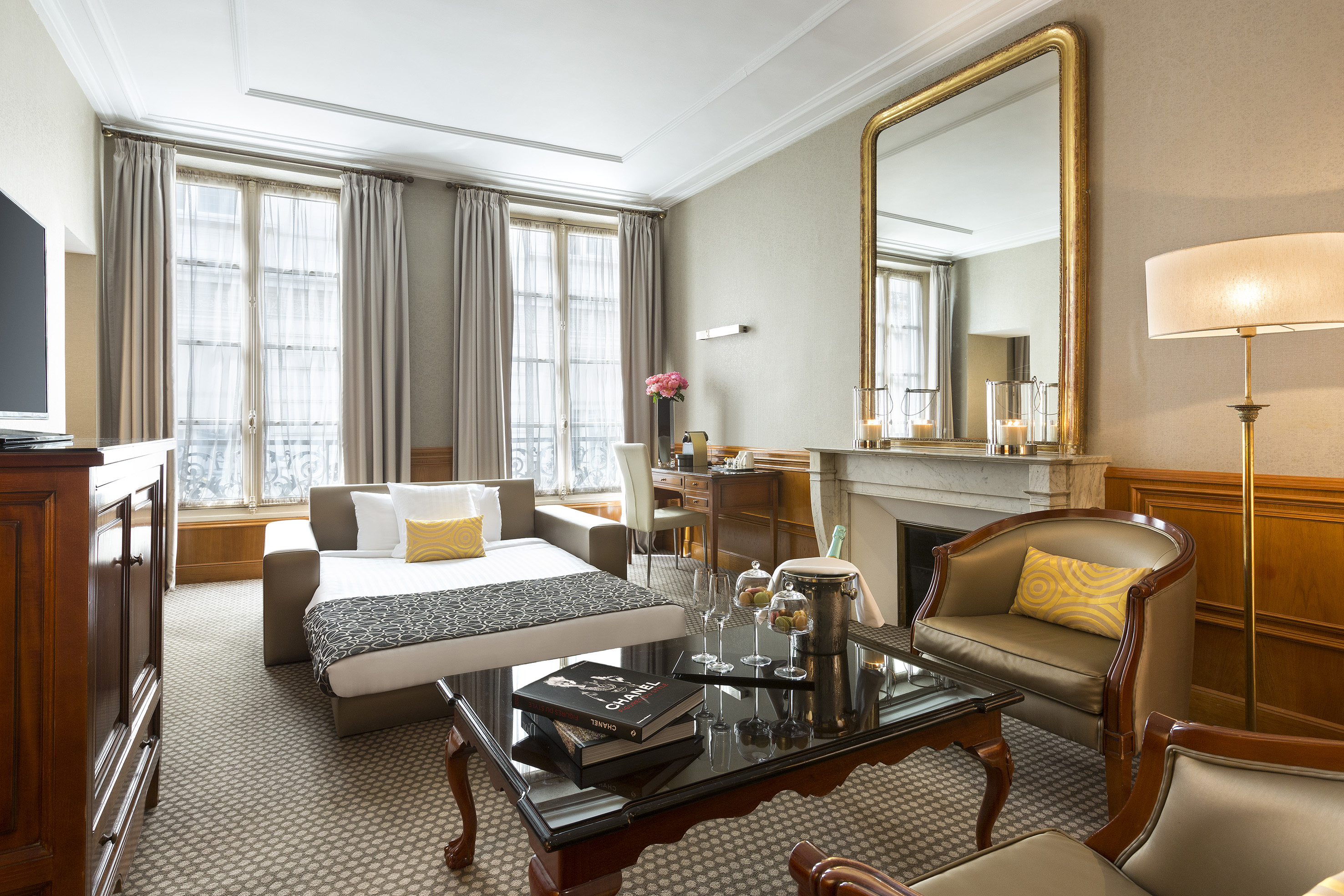 Elegant hotel suite with sofa bed, living area, fireplace, and champagne.