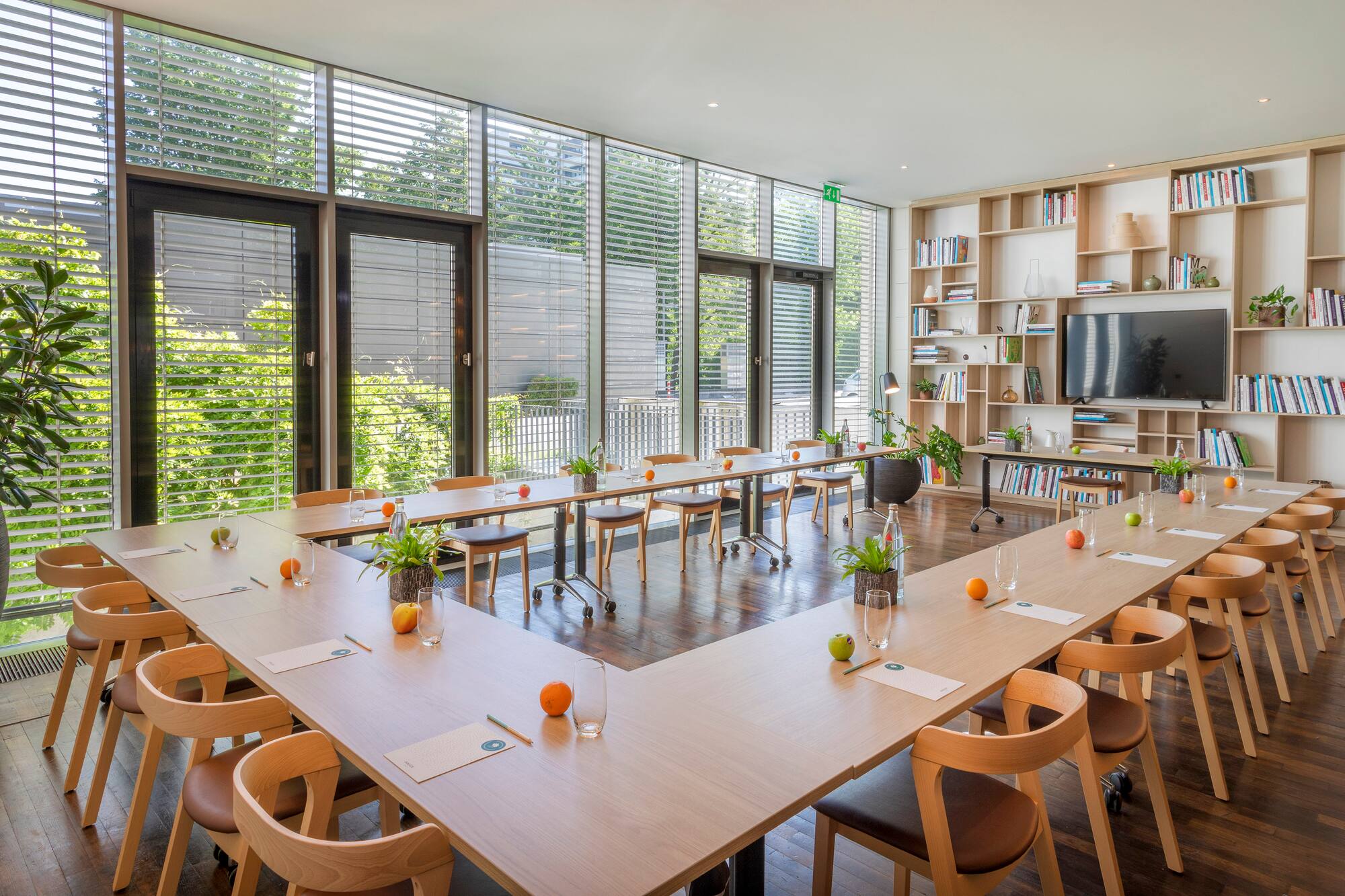 U-shaped meeting room with natural light, large windows, and bookshelf.