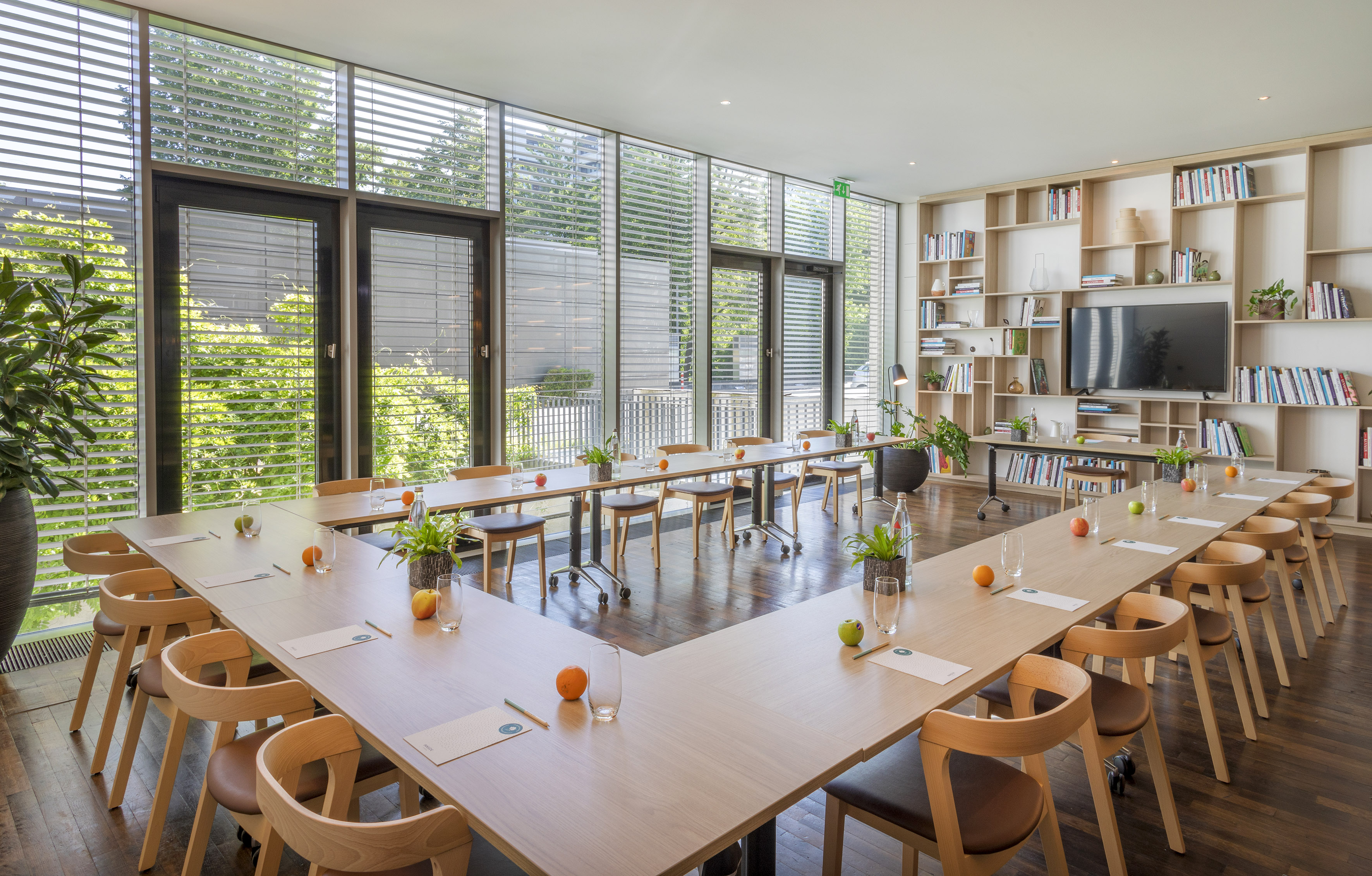 U-shaped meeting room with natural light, large windows, and bookshelf.