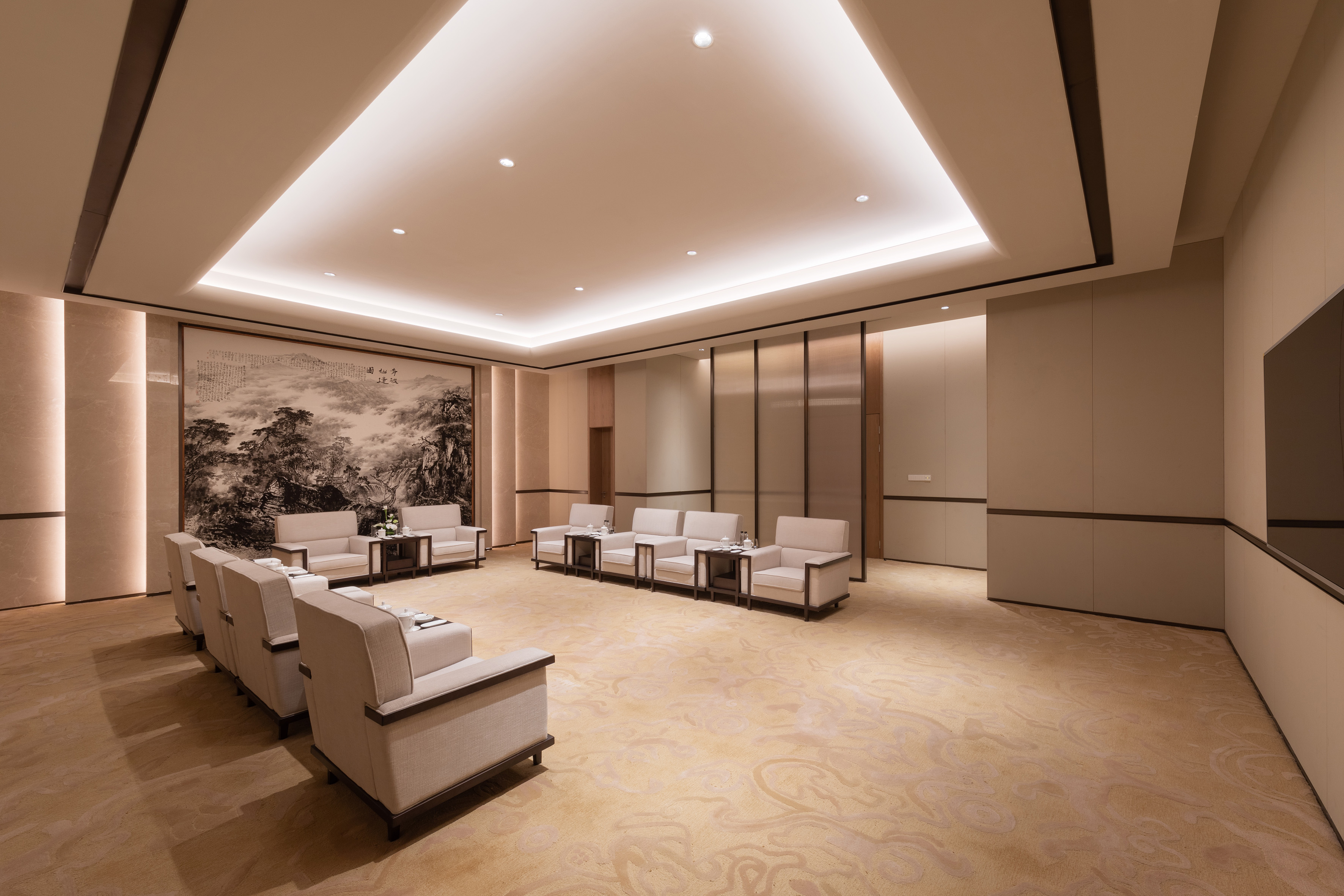 Modern executive lounge with beige armchairs, elegant landscape mural.