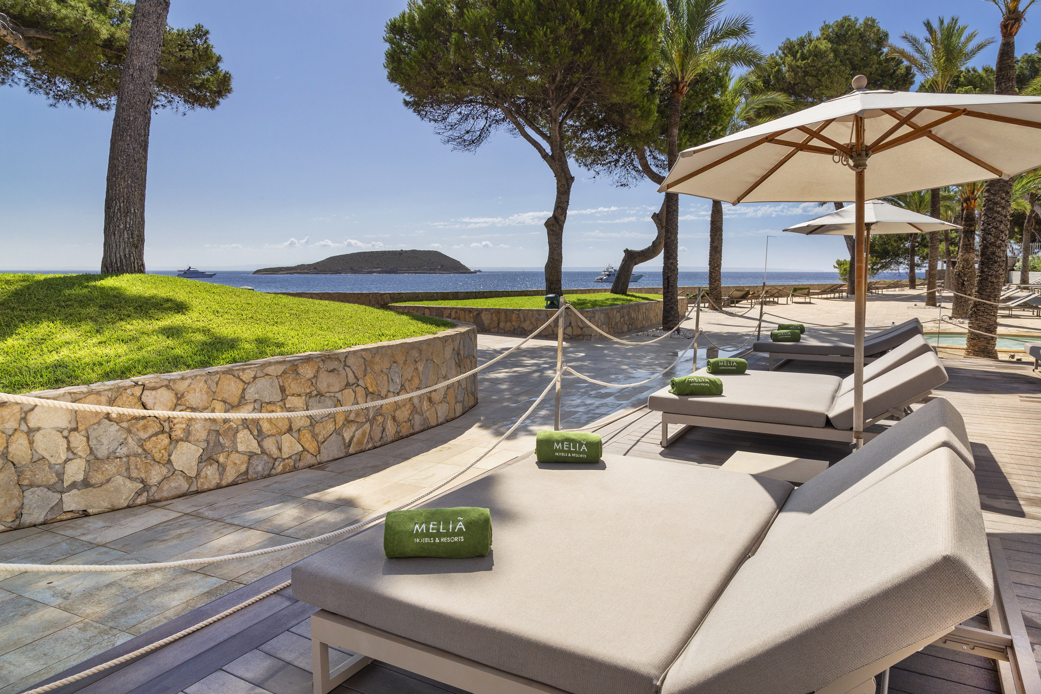 Luxury Meliá resort with sun loungers, sea view, island, and palm trees.